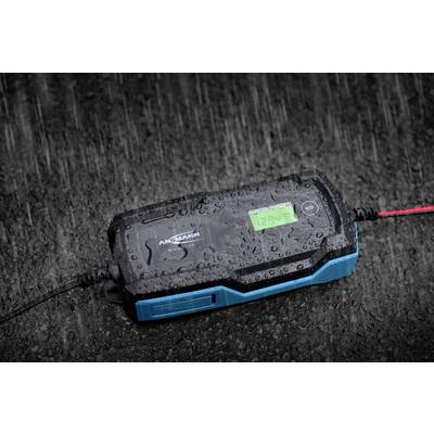 En batteriladdare ligger på våt asfalt under kraftigt regn.