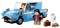 Lego-scen: Två figurer bredvid en blå bil. En figur kör bilen, den andra håller en mugg. En vit uggla sitter intill.