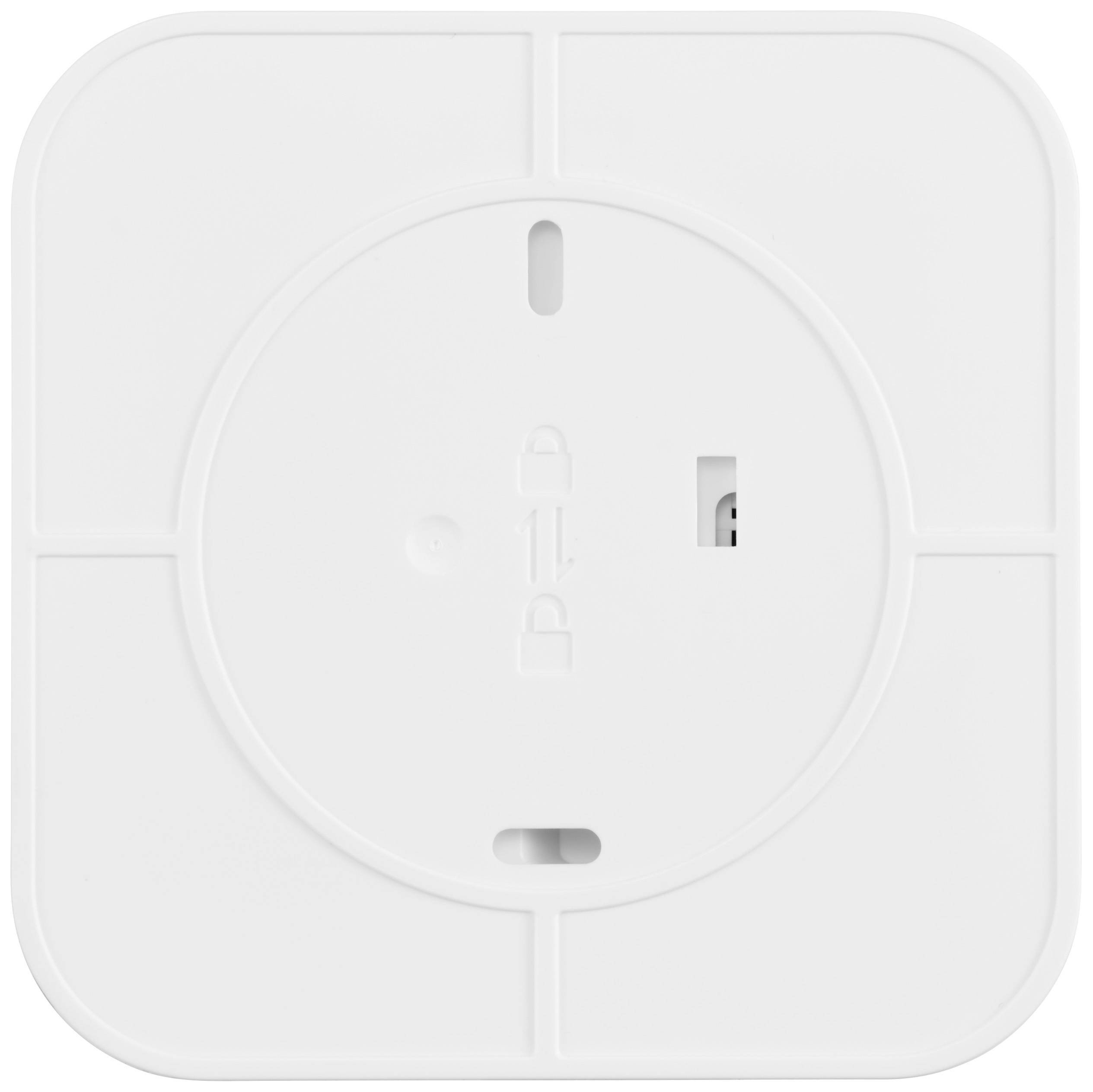 Baksidan av en fyrkantig vit enhet, troligen en switch eller sensor, med låssymboler och switchöppning.