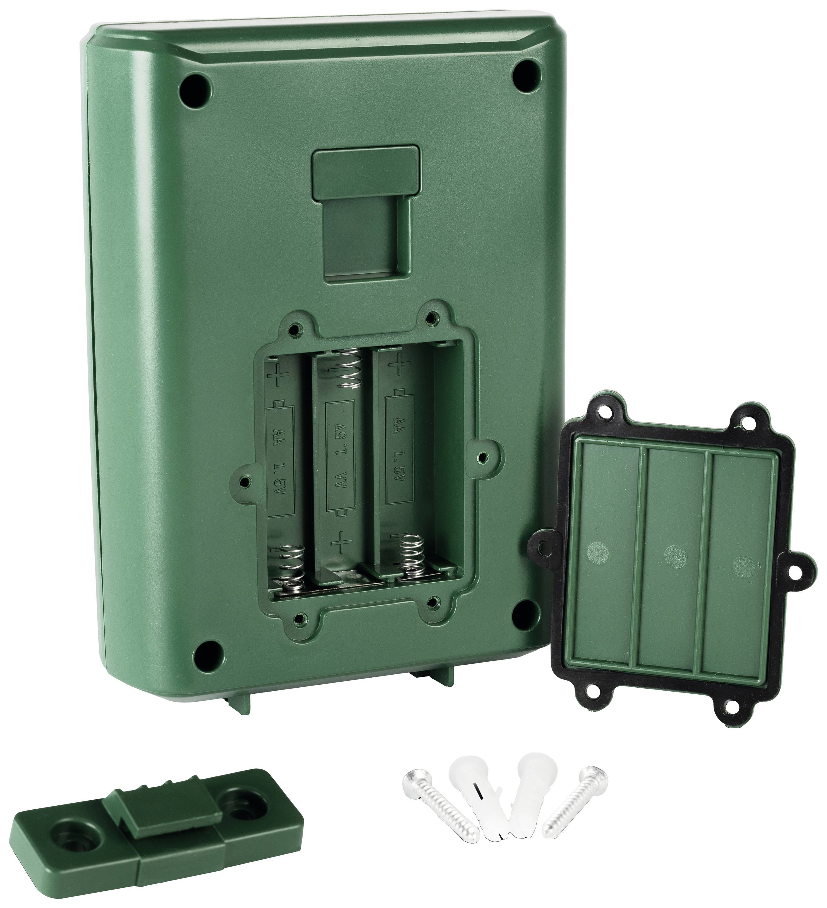 Grönt batterifackhölje med borttaget lock, batteriplatserna är synliga. Skruvar och väggfäste bredvid.