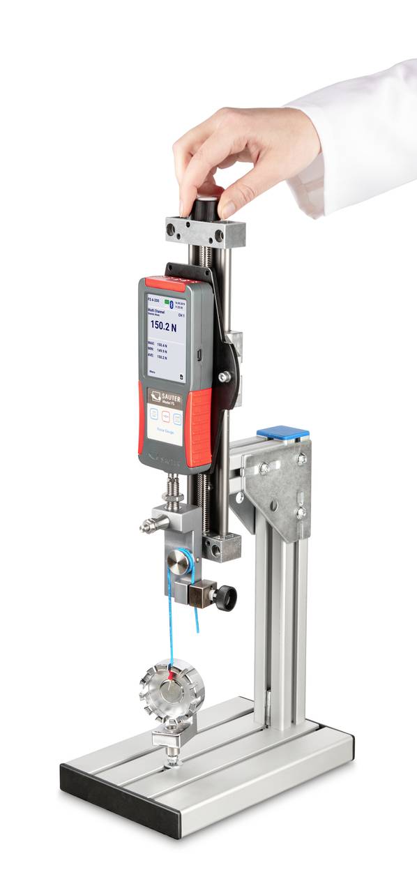 Handmanövrerad provningsutrustning för att mäta dragbrottlast hos ett objekt, digital avläsning visar 152,8 N, monterad på metallställning.