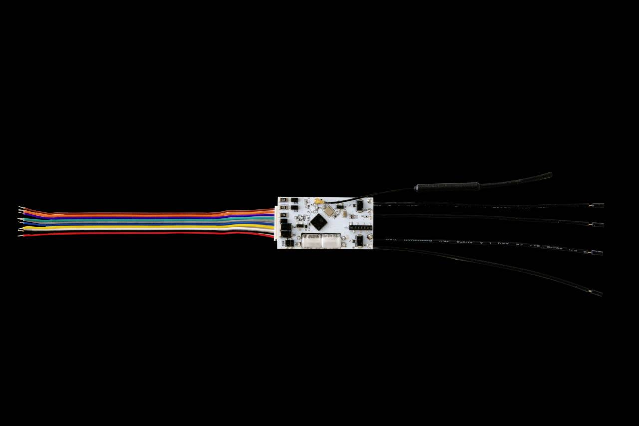 Elektronisk krets med lödade trådar på svart bakgrund. Olika färger på trådarna indikerar olika funktioner.