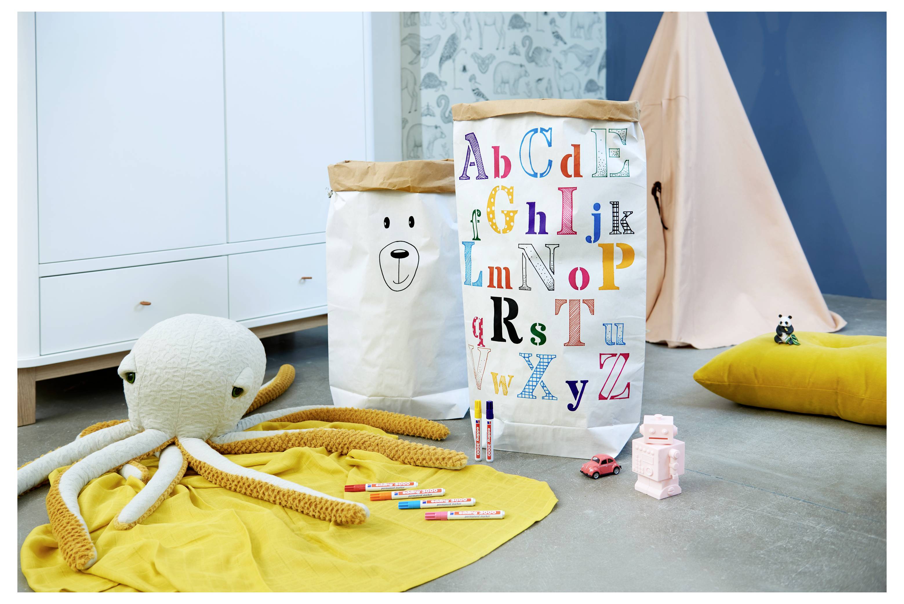 Barnlekrum med en leksaksöktopus, alfabetbokstav, kritor och små leksaker på mattor och kuddar.