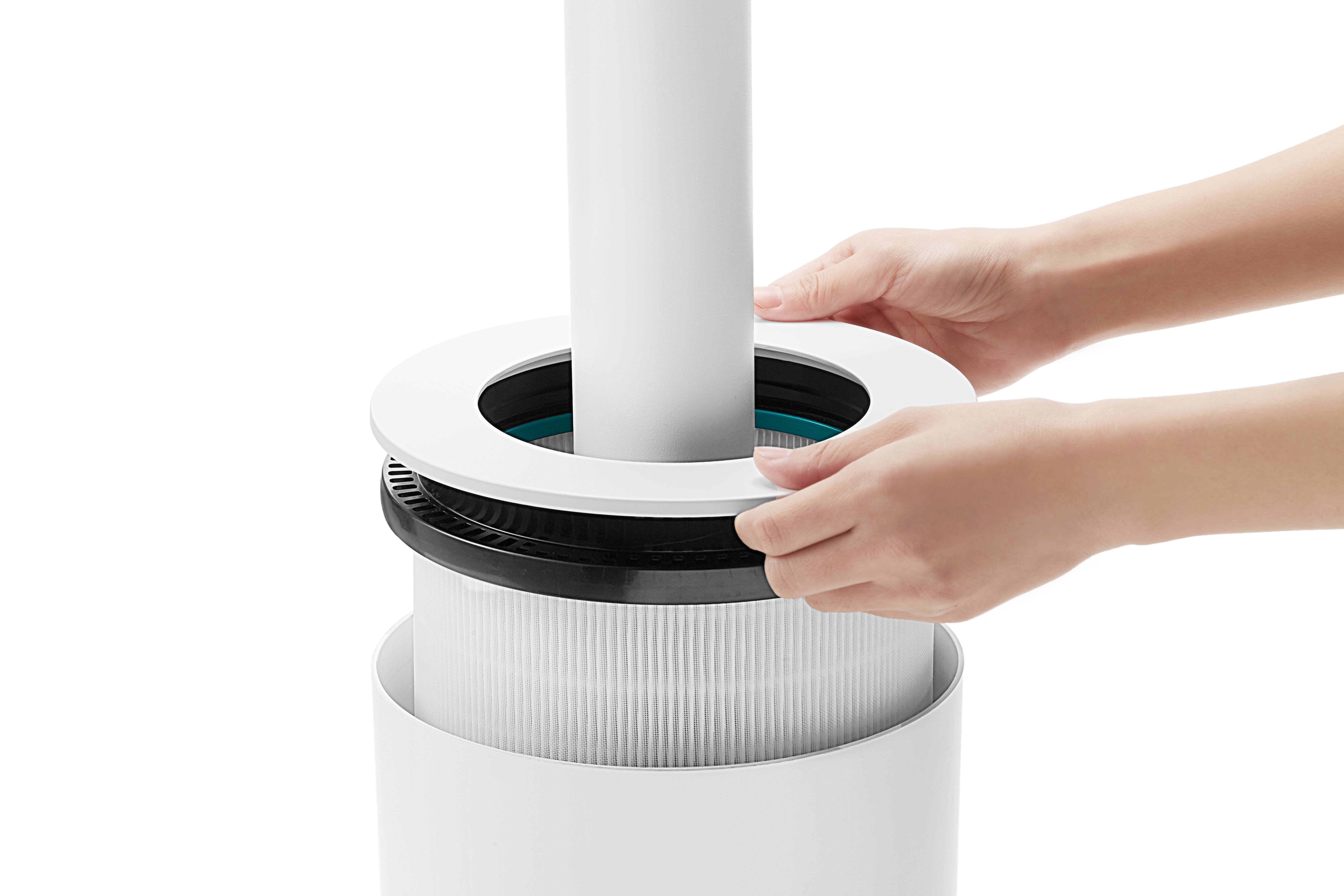 Två händer monterar ett luftfilter i en rund, vit apparat. Filtret har en cylindrisk konstruktion och passar in i enheten.