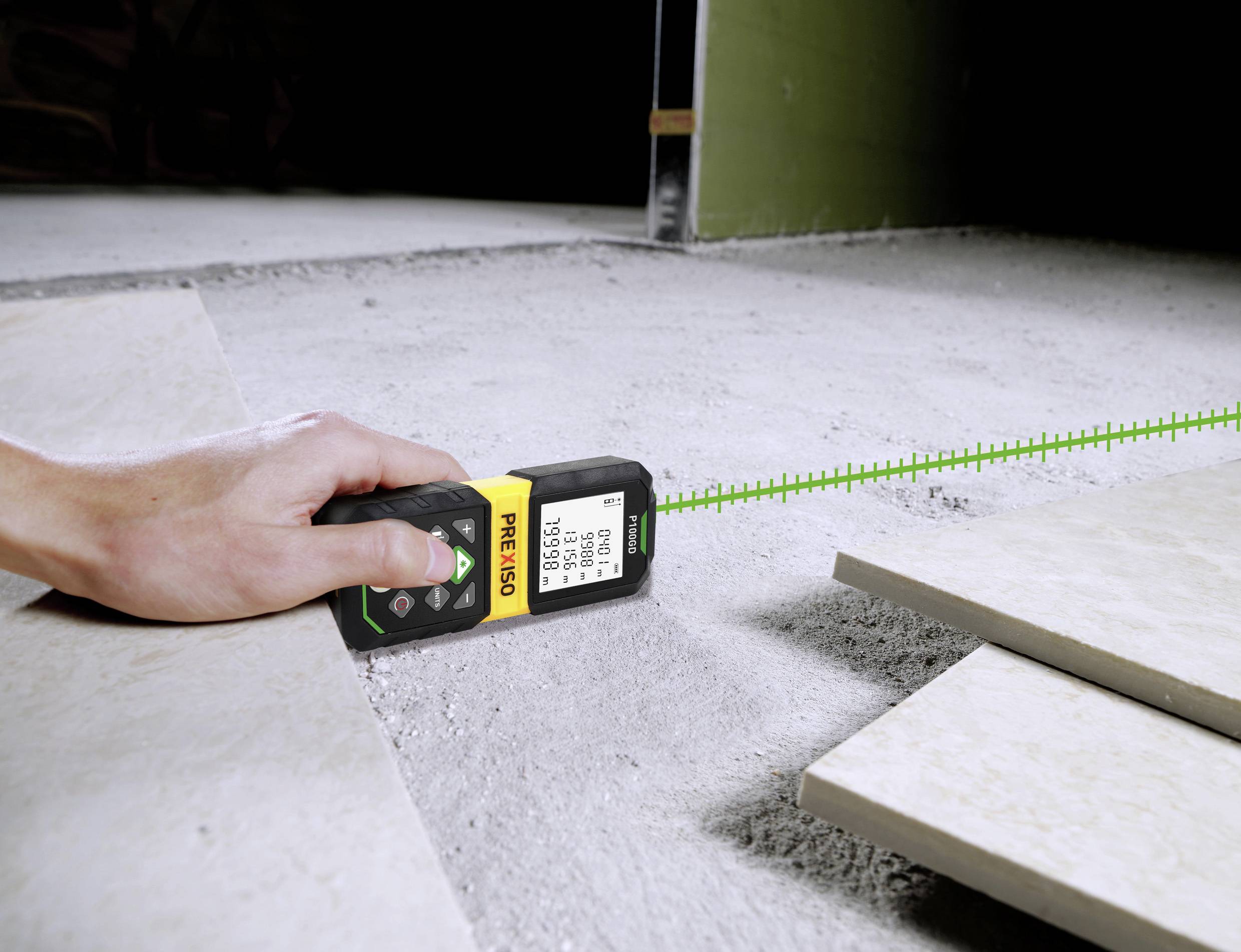 En hand håller ett lasermätinstrument över ett betonggolv och mäter avståndet till golvplattorna. Instrumentet visar den uppmätta distansen.