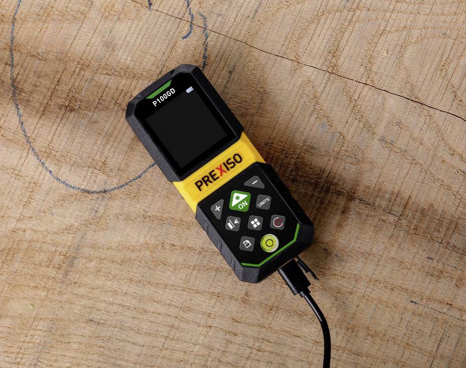 En digital mätare med skärm och knappar ligger på ett trägolv. Den är ansluten med en kabel och visar 'P 1000'.