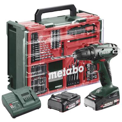 Metabo trådlös borrmaskin med borrbitar, två batterier, laddare och röd bärväska i en transparent förvaringslåda.