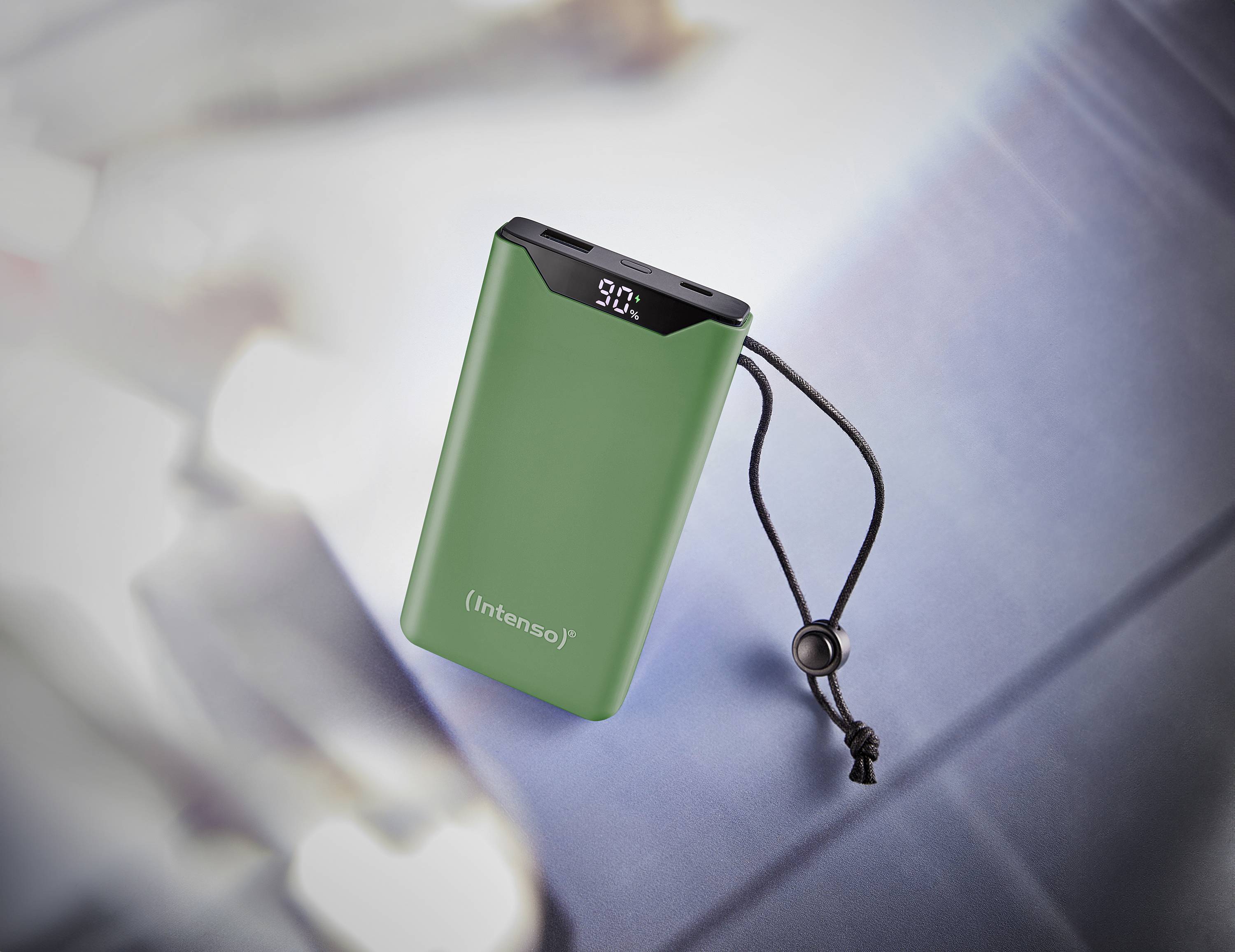 En grön powerbank med en digital display på ovansidan som visar '90%'. Den har ett svart bärhandtag.