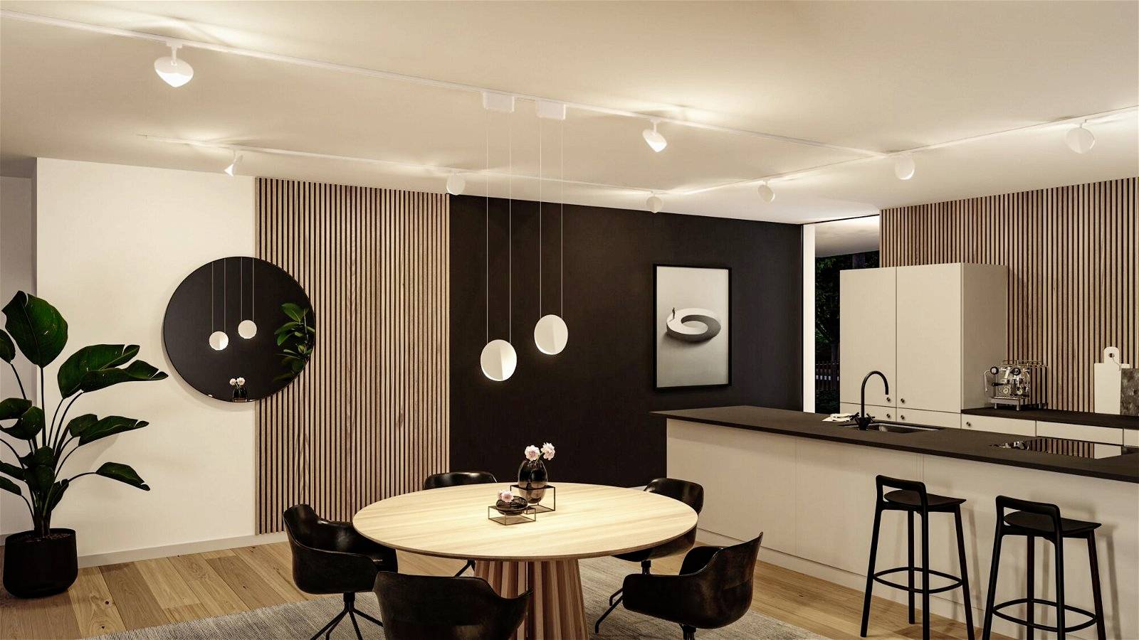 Modern matlagnings- och köksområde med trädetaljer, runt matbord och hängande lampor. Elegant inrett med mörk accentvägg.