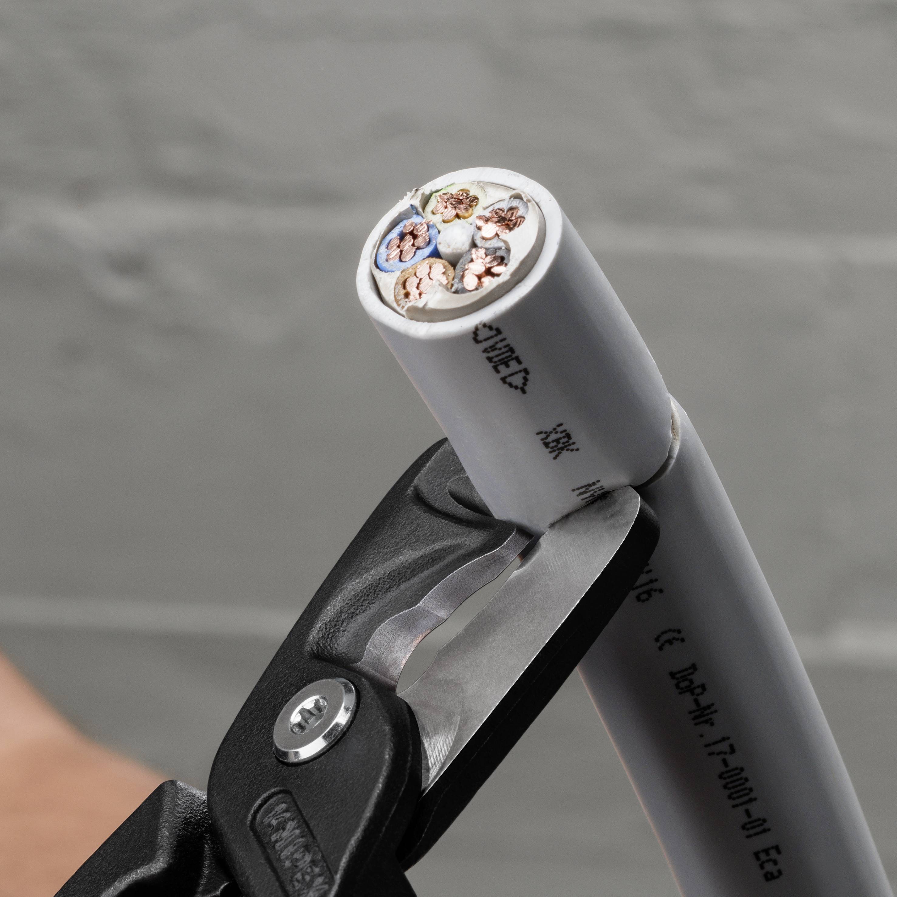 En kabel kapas med ett verktyg som visar de färggranna trådarna inuti. Fokus ligger på skärningens precision.