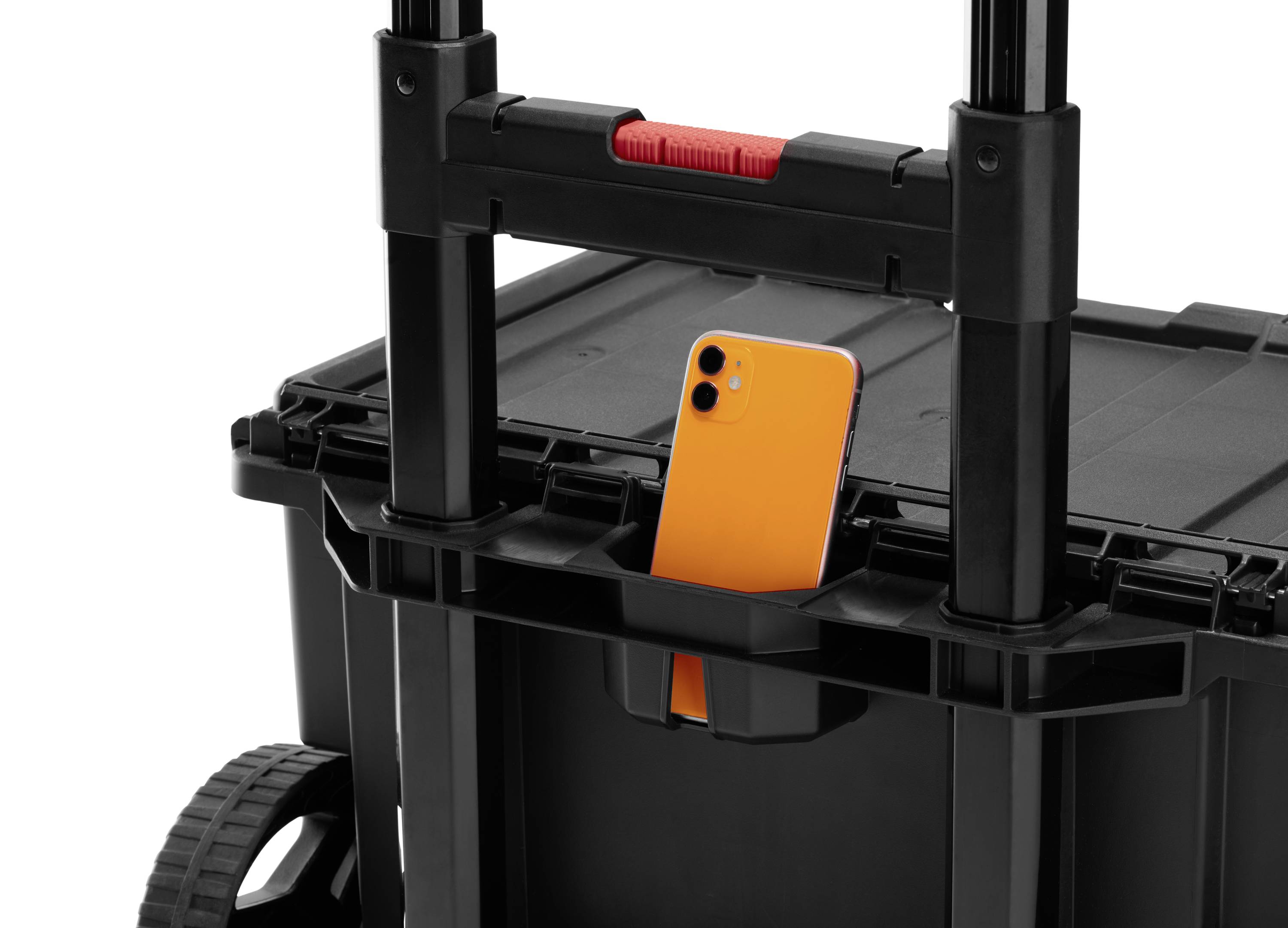 En orange mobiltelefon sitter i hållaren på en svart transportvagn med utdragbart handtag.