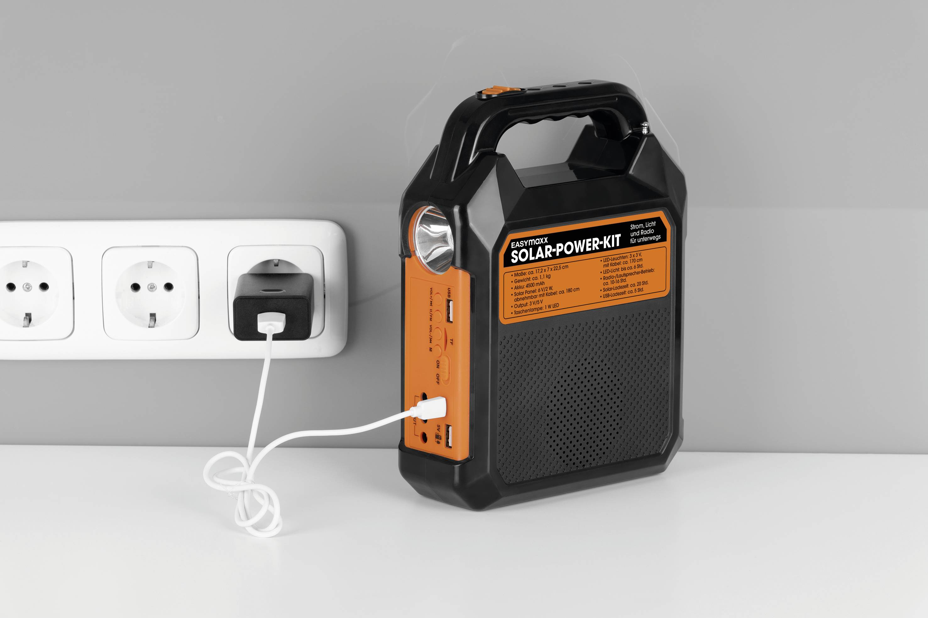 En bärbar, orange-svart solarkraftsenhet ansluts till ett vägguttag. Den har flera anslutningar för enheter.