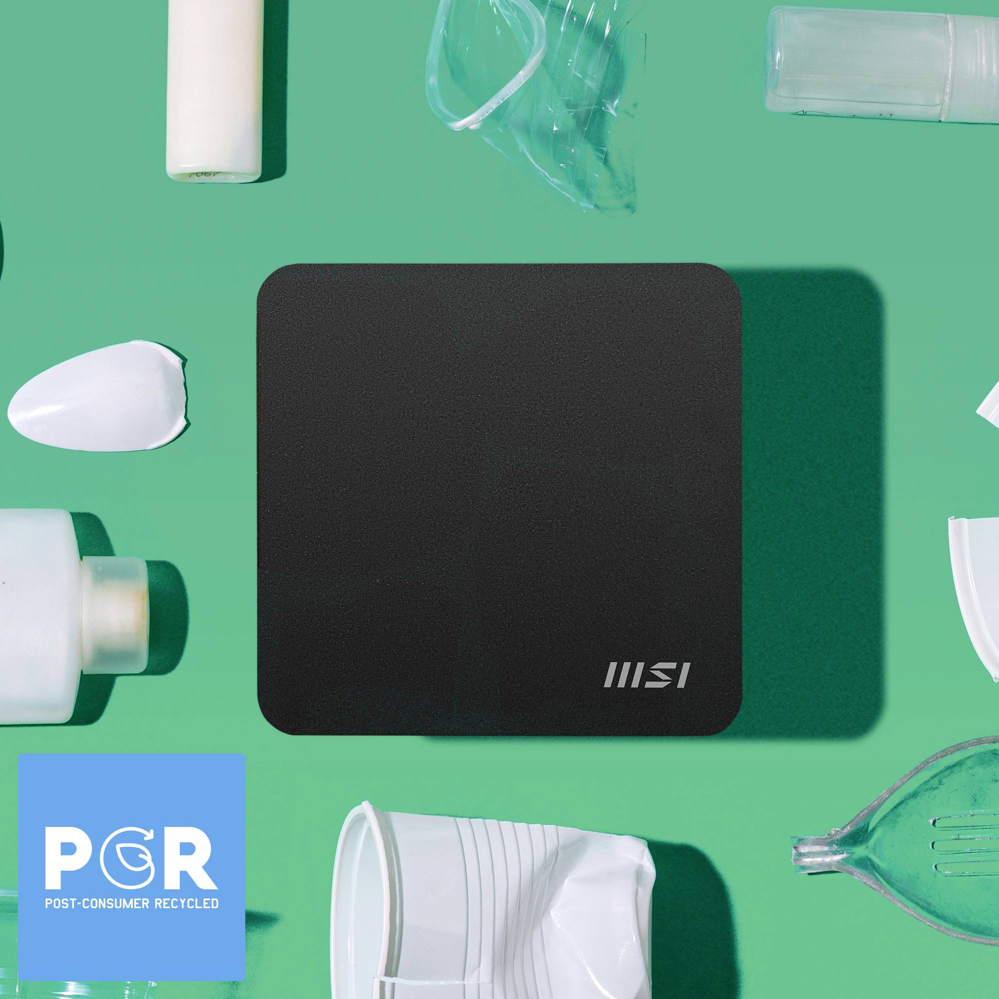 En svart, rektangulär MSI-platta omgiven av olika vita plastföremål på grön bakgrund. 'PCR - Post-Consumer Recycled' logotyp längst ner till vänster.