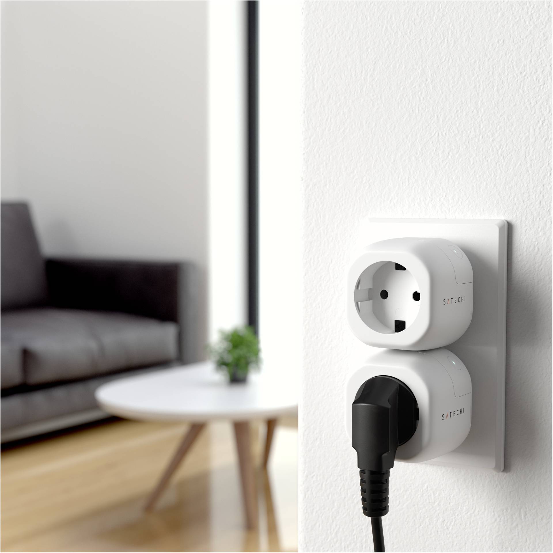 Vägguttag med dubbel adapter, där en kontakt är isatt. I bakgrunden suddigt ett bord och en soffa synliga.
