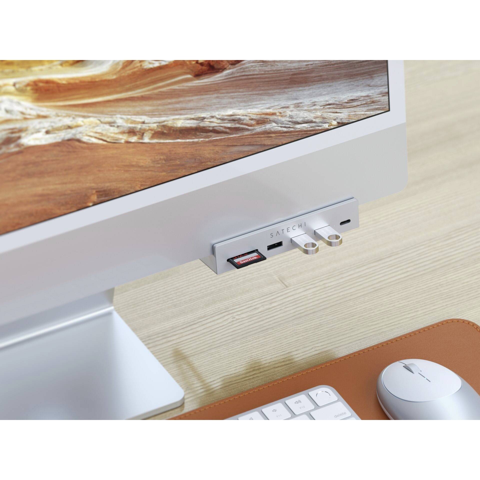 En skärm med en ansluten adapter som har flera USB- och kortplatser står på ett träskrivbord.