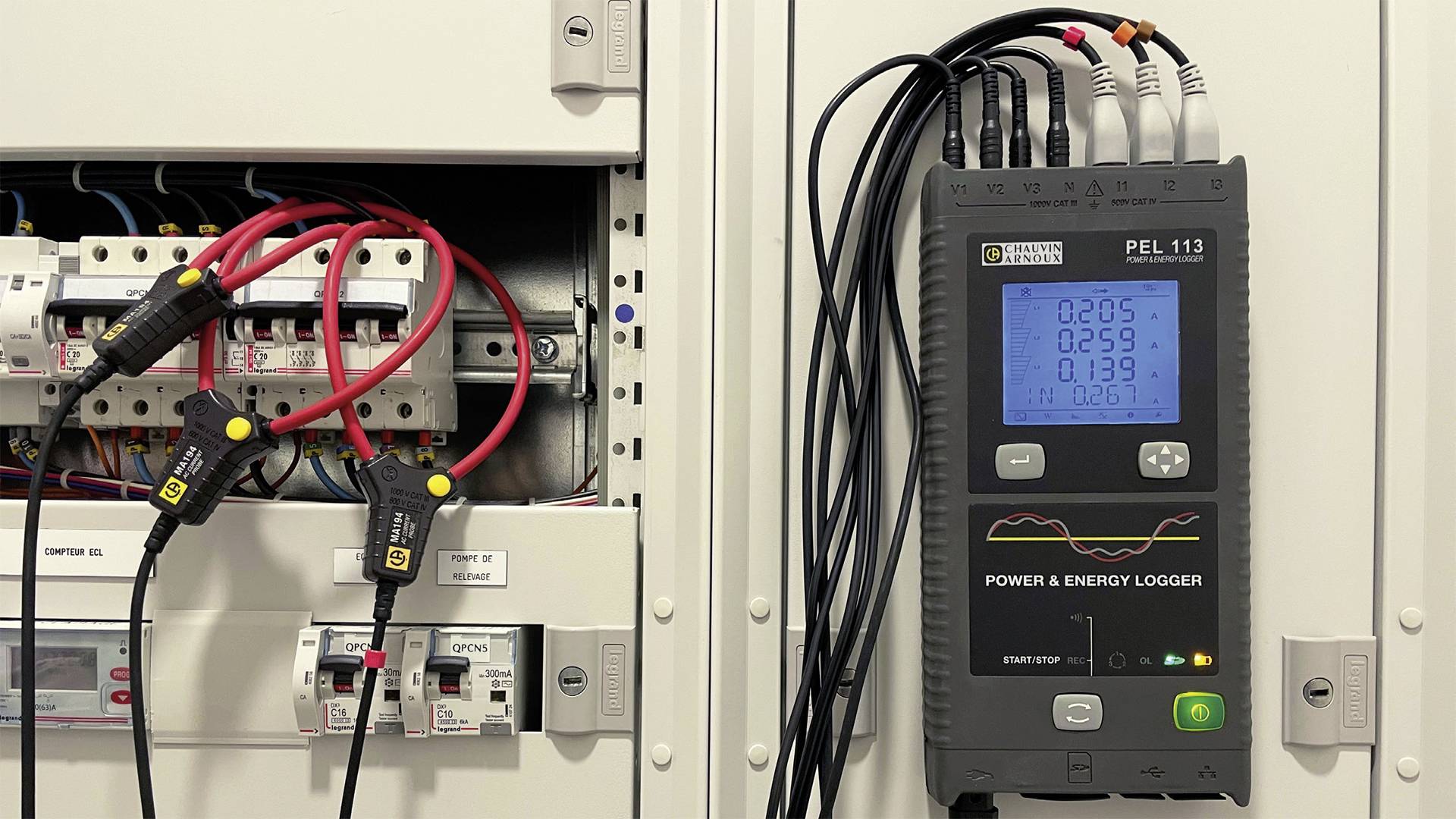 En energilogger mäter elektriska värden i en elcentral, visade på enhetens display med kabelanslutningar till modulerna.