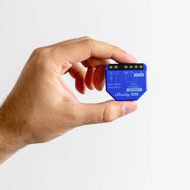 En hand håller en liten, blå elektronisk enhet med tekniska specifikationer och anslutningar, sannolikt en relämodul.