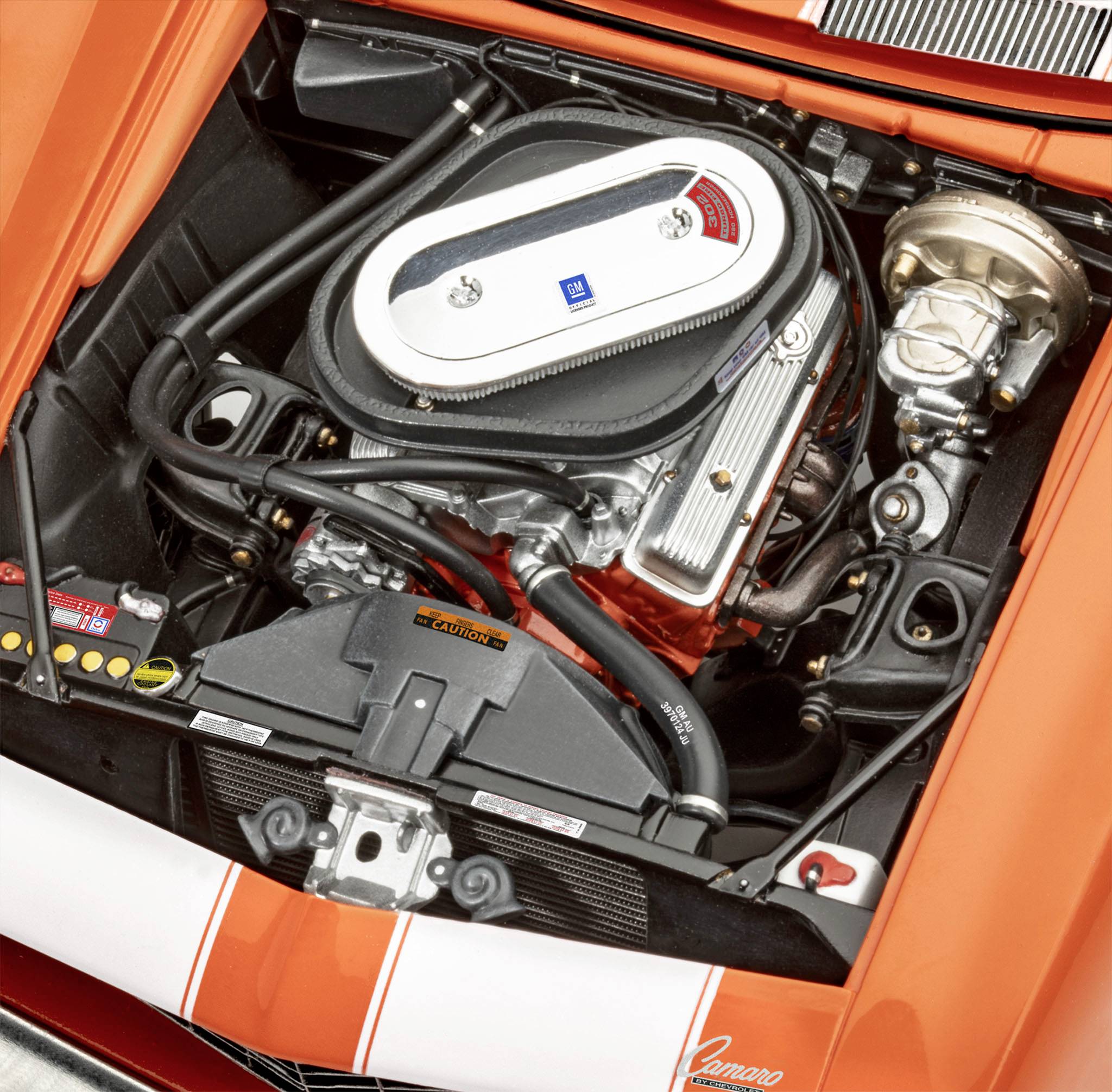 Ett öppet motorrum i en orangefärgad sportbil som visar den detaljrika motorn med silver- och svarta komponenter.