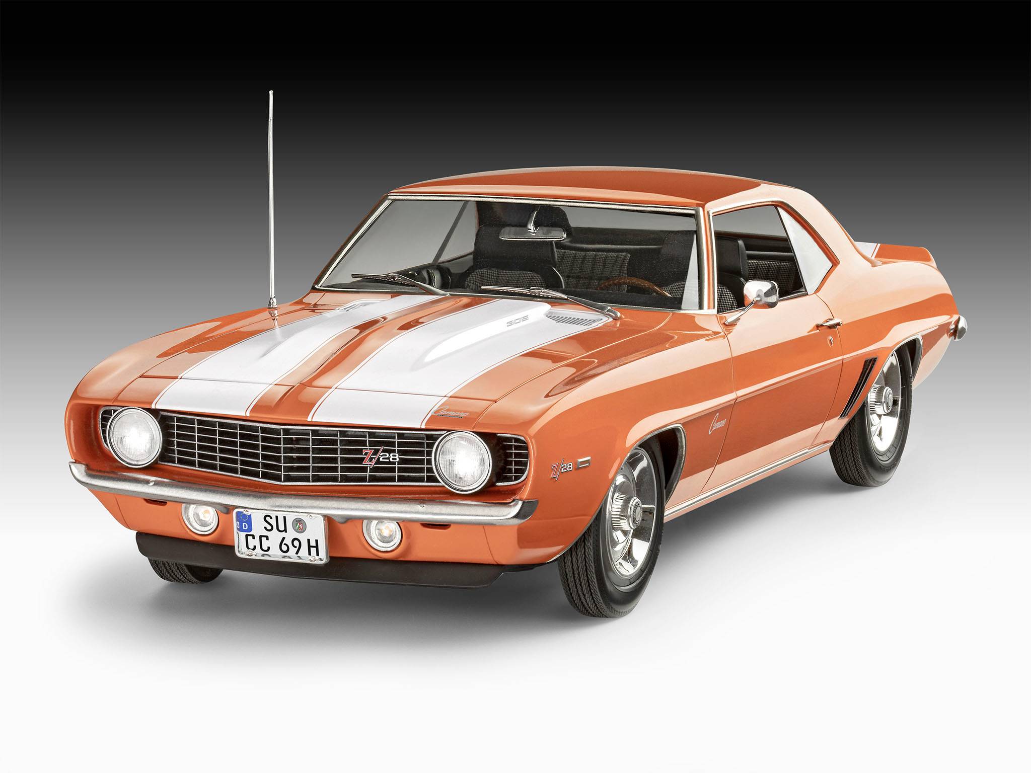 En orange-vit veteranbil, sannolikt en Chevrolet, visar upp en slank, klassisk design med två dörrar.