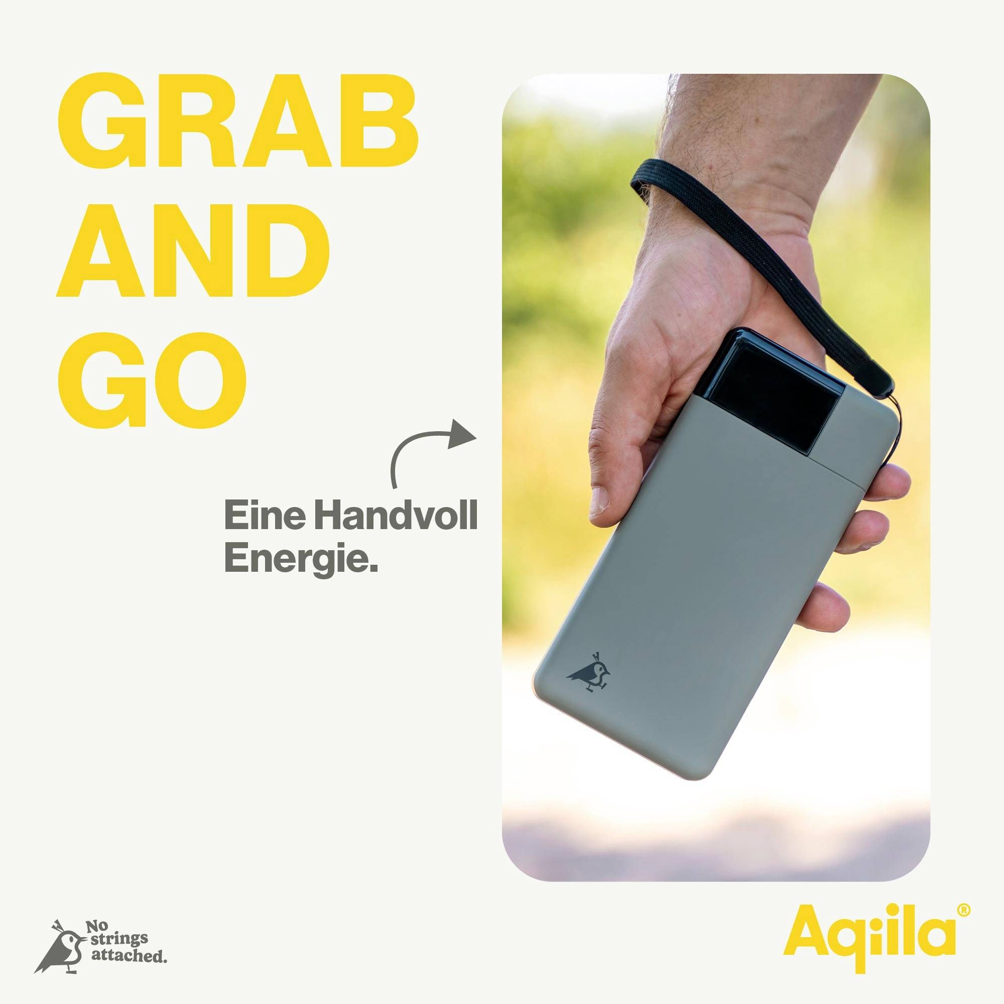 Hand håller en kompakt grå powerbank med svarta batteriladdningsindikatorer. Text: 'GRAB AND GO', 'En handfull energi.' Varumärkets logotyp längst ner till höger.