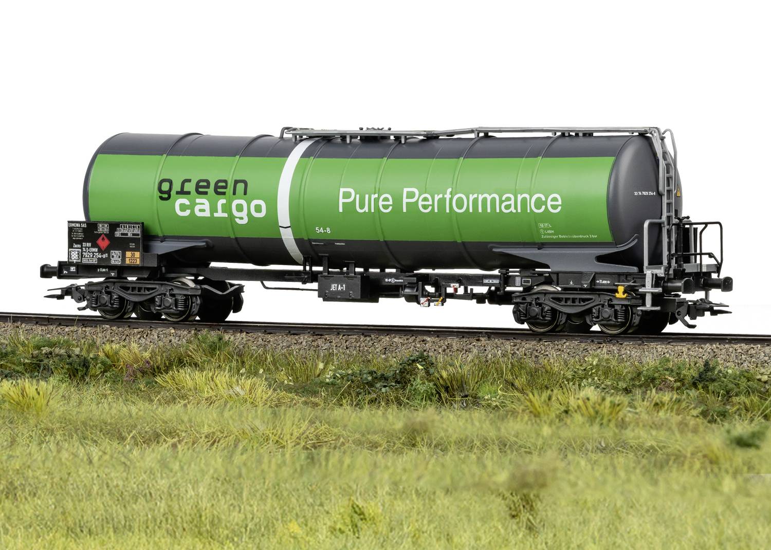 Grön godsvagn med inskrifterna 'green cargo' och 'Pure Performance' på järnvägsspår; sidovy mot gräslandskap.