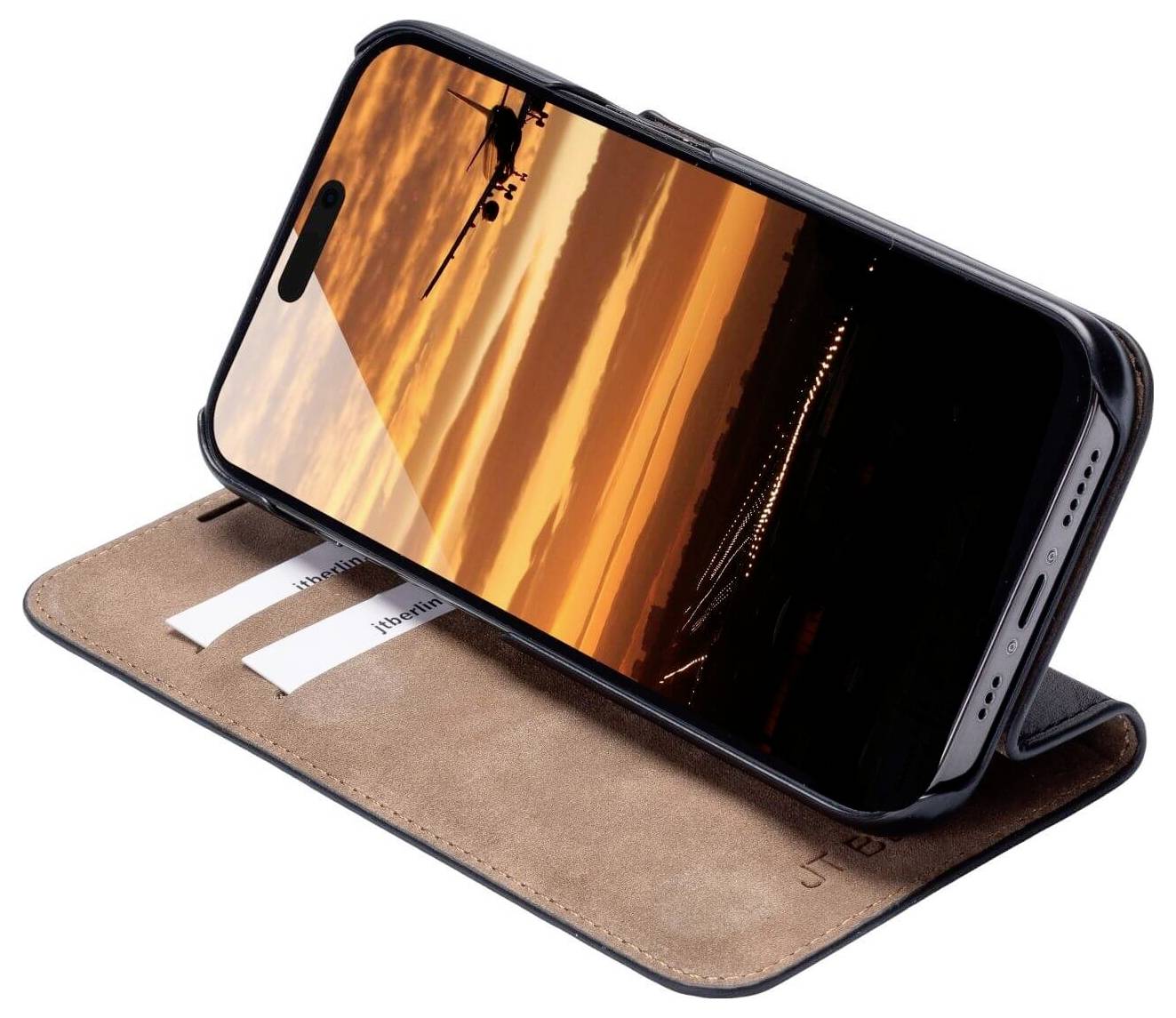 En smartphone i ett brunt fodral, placerad i en horisontell vinkel. Skärmen visar en solnedgång med ett flygplan.