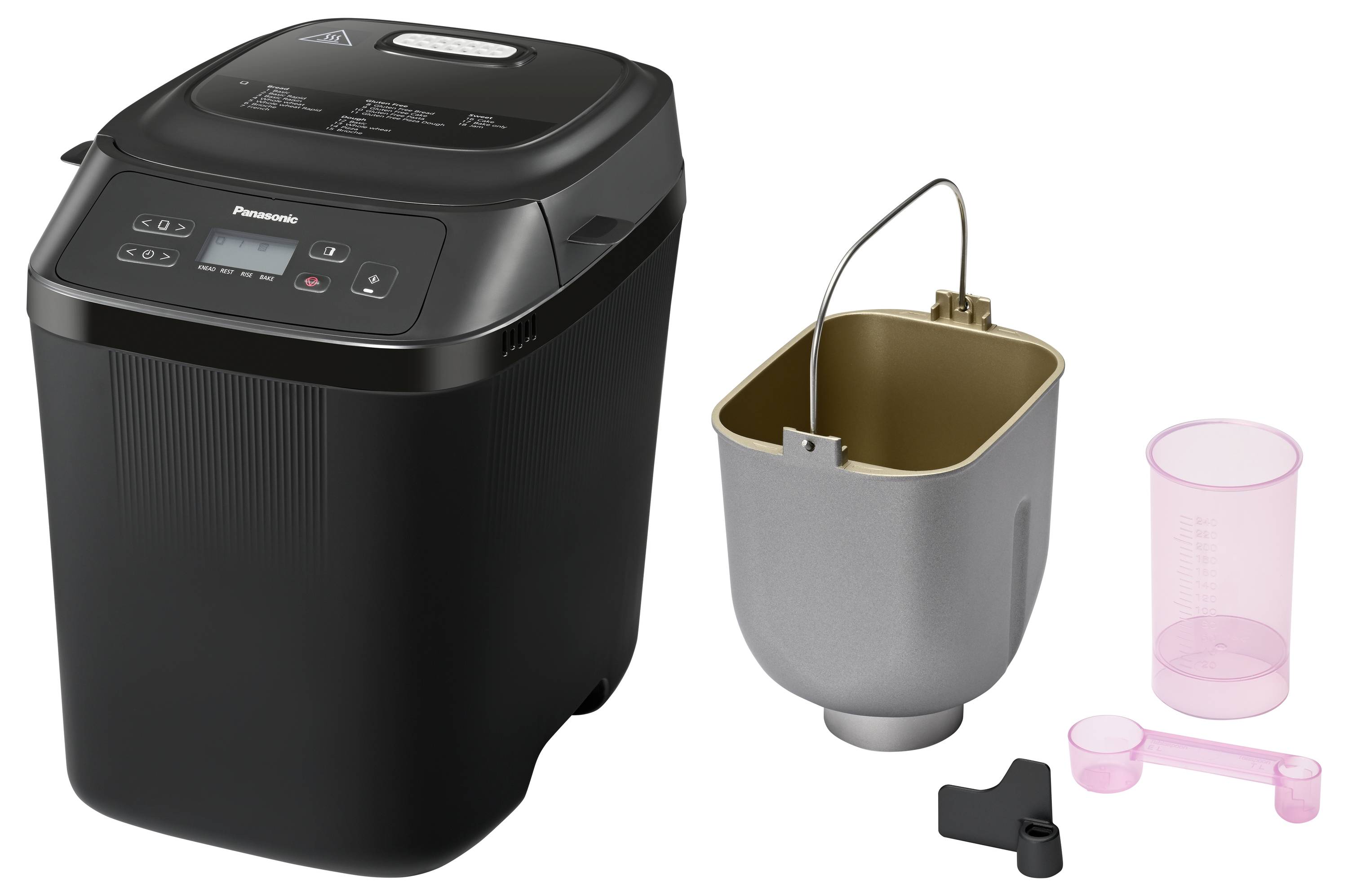 En svart brödbakningsmmaskin bredvid en avtagbar bakform och mätutrustning, klargjord för hembakning av bröd.