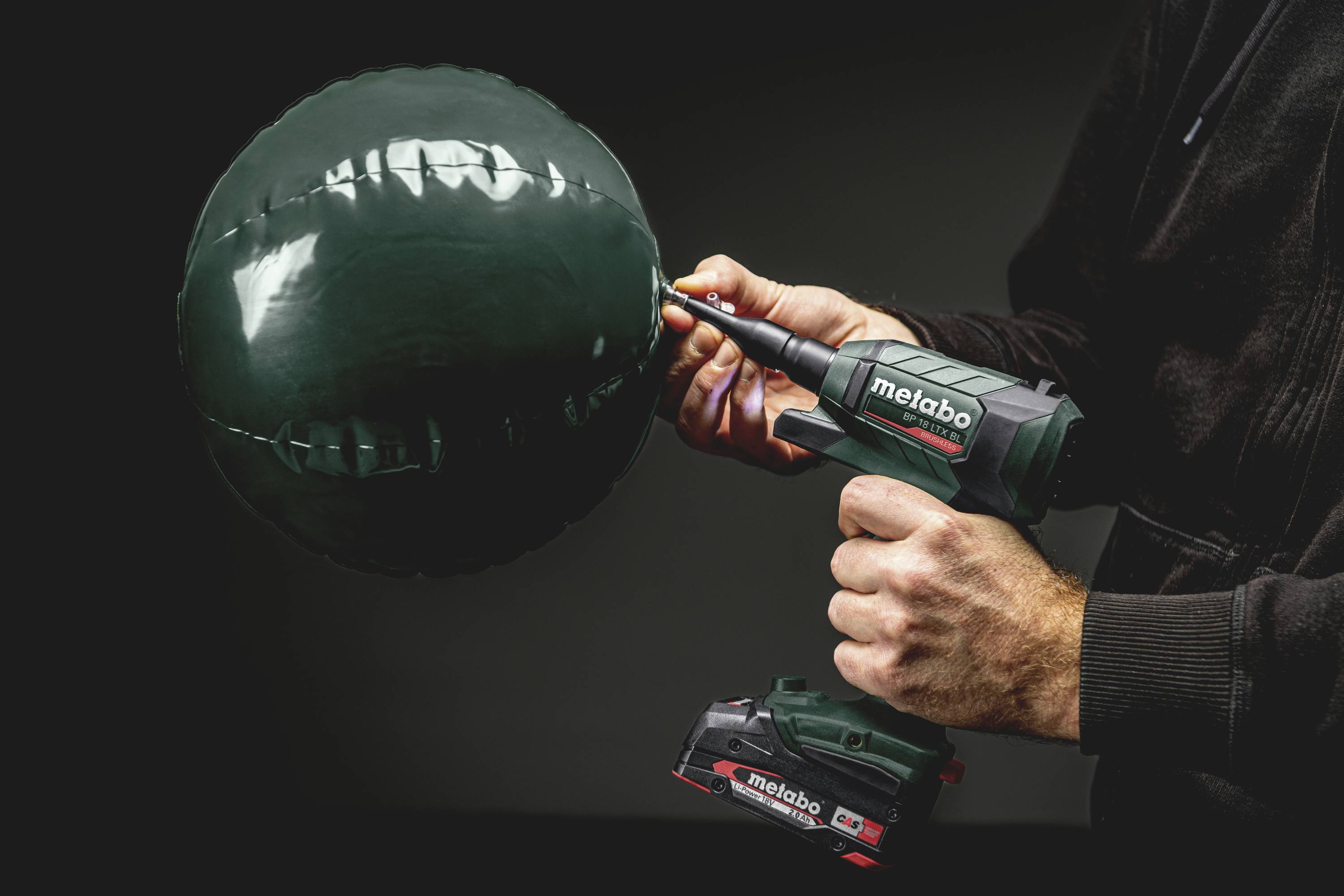 En person testar styrkan hos en grön boll med ett Metabo-verktyg. Bollen verkar vara stabil och motståndskraftig.