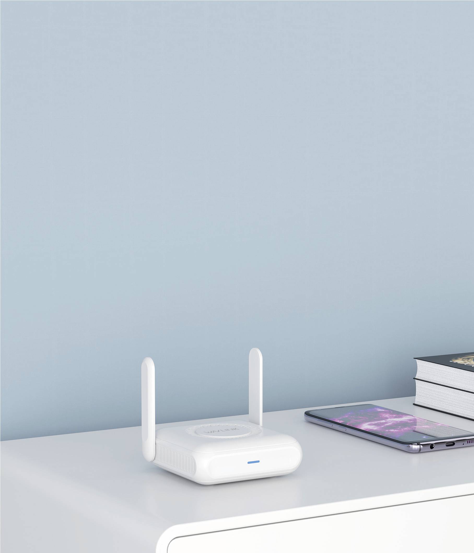 En vit WiFi-router med två antenn står på ett vitt bord bredvid en smartphone och böcker framför en blå vägg.