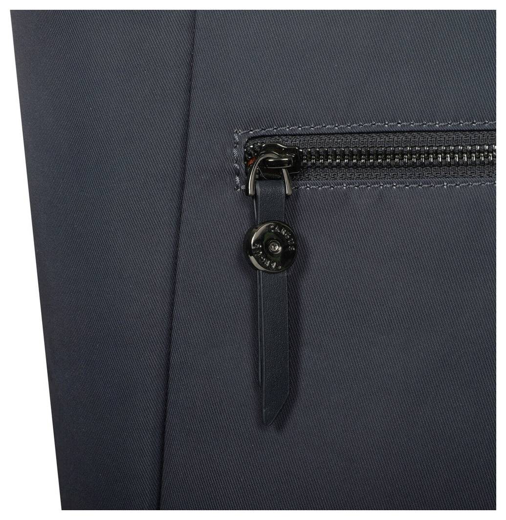 Närbild av ett mörkgrått tygmaterial med en vertikal dragkedjeficka och en rund logotyp på dragkedjans slinga.