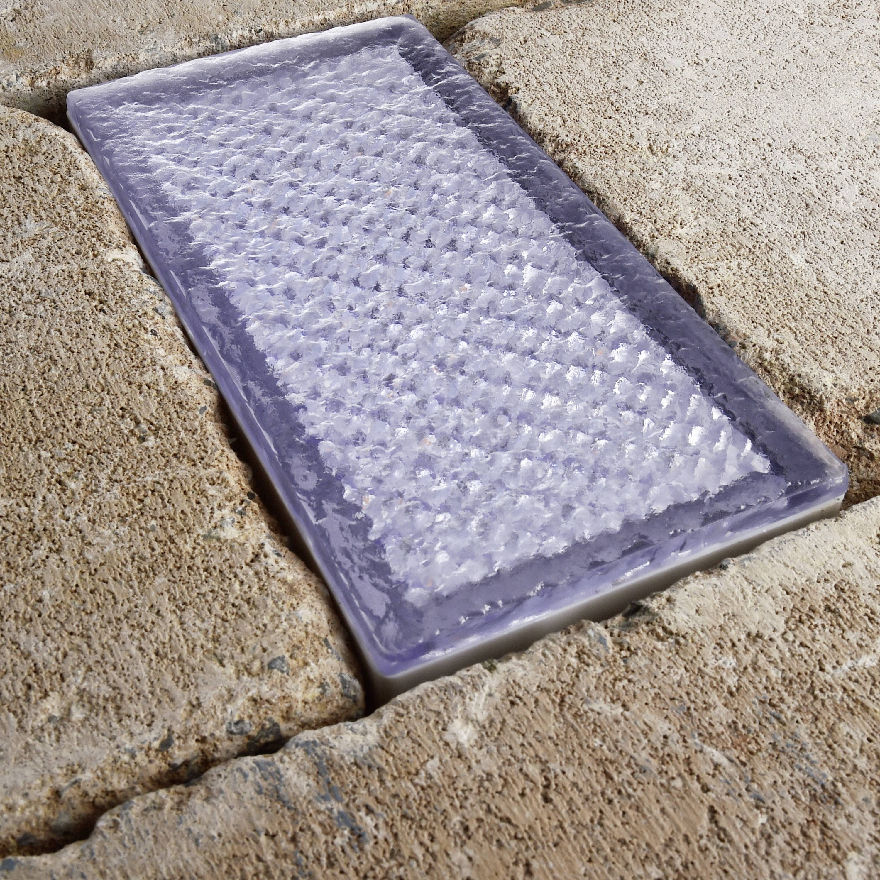 Gångväg med platta, strukturerade glasstenar inbäddade i gatsten. Belysningseffekt genom ljusinsläpp.
