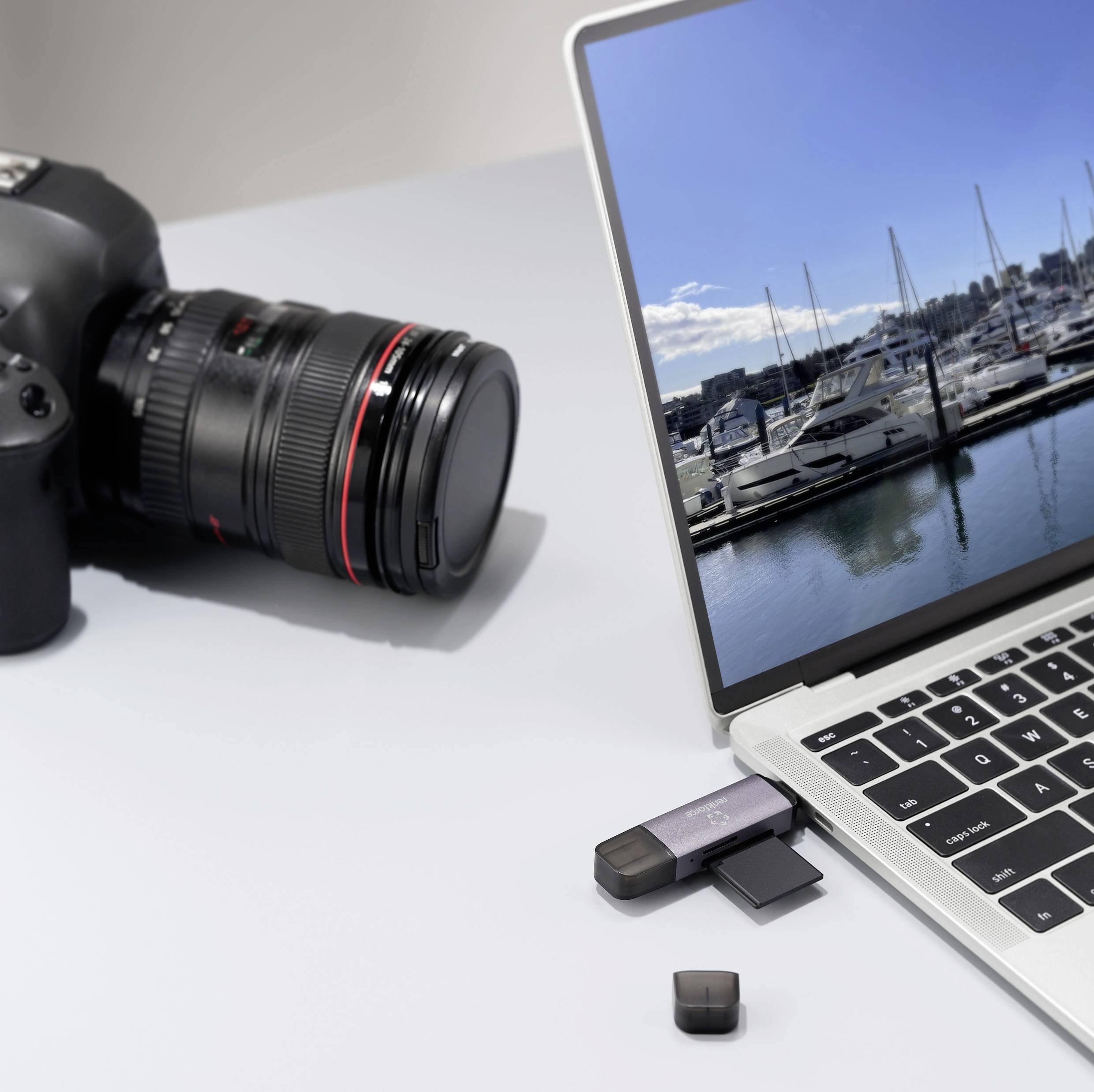 Bärbar dator med ett foto av en yachthamn på skärmen, bredvid en kamera och USB-minnen; tema: förbindelsen mellan fotografi och teknik.
