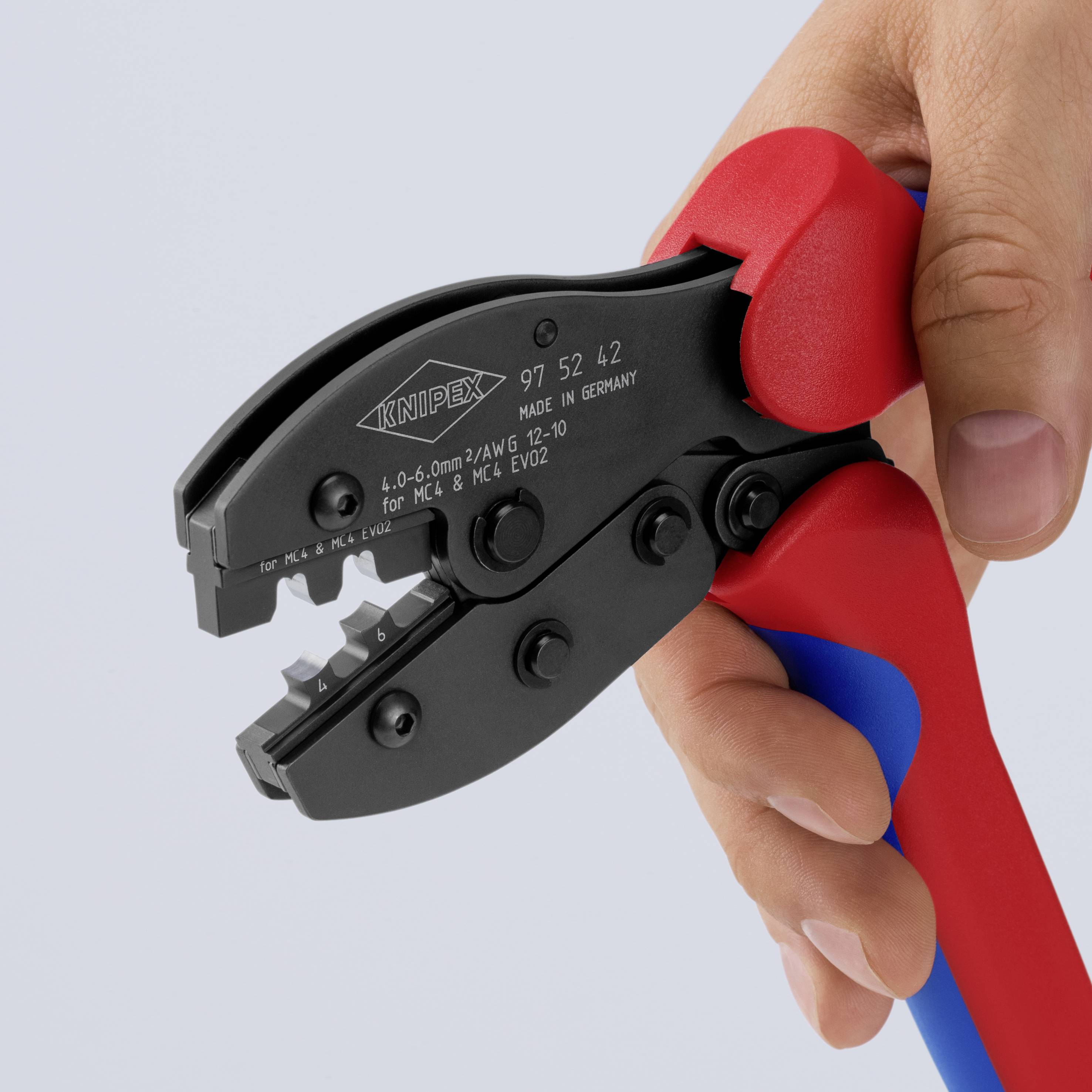 Ett verktyg för crimpning med rött och blått handtag hålls i en hand, lämpligt för isolerade elektriska kontakter.