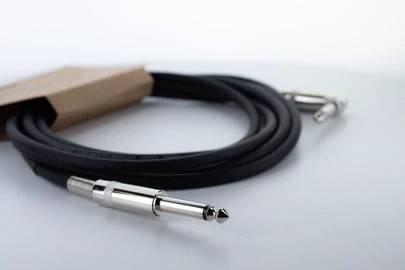 En svart audiokabel med en metallkontakt är ihopvriden. Den ligger på en vit bakgrund, och kontakten är tydligt synlig.