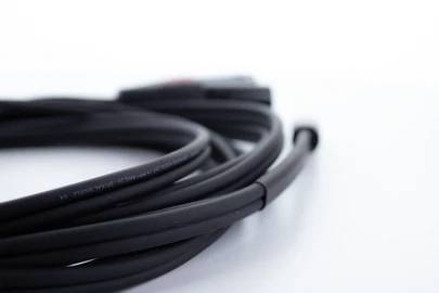 Ett svart kabel med ansluten kontakt ligger på en vit yta.