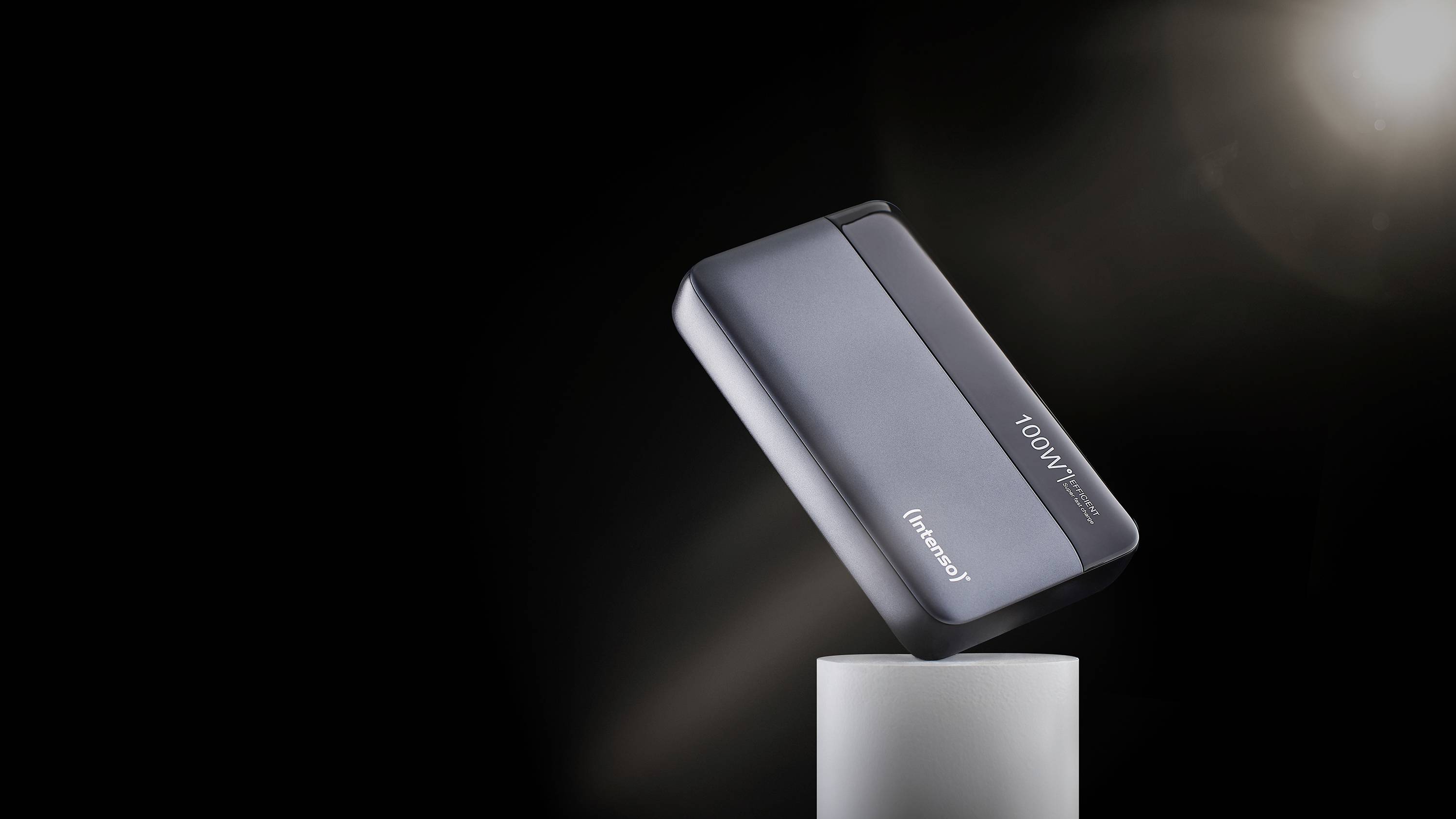 En powerbank med texten '100W' lutar på en piedestal framför en mörk bakgrund.