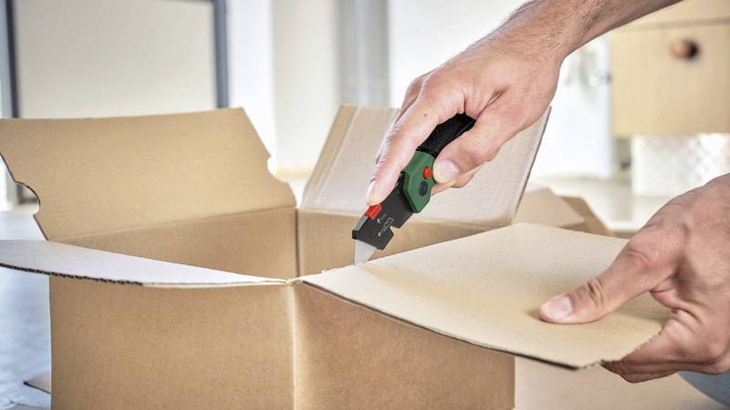 En person klipper upp en kartong med en hobbykniv, troligen medan han/hon packar upp ett paket.