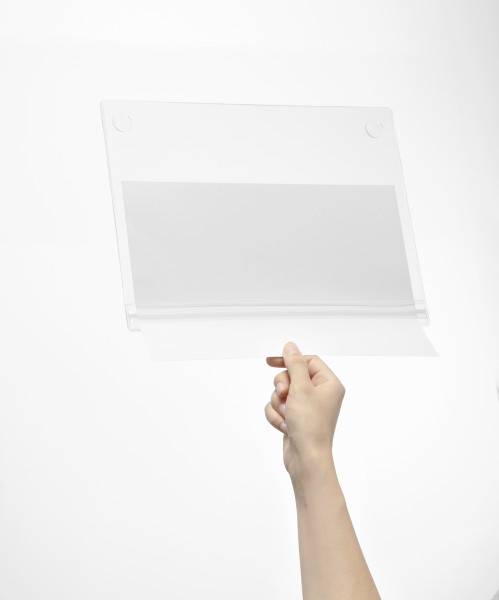 En hand håller en genomskinlig, rektangulär plastskärm framför en vit bakgrund.