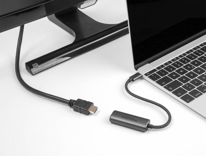 En adapter ansluter en bärbar dator till en extern skärm via en HDMI-kabel. Både laptopen och skärmen är svarta.