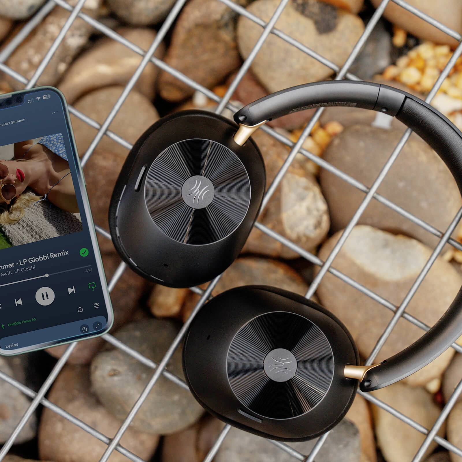 Hörlurar ligger på stenar bredvid en smartphone som spelar musik.