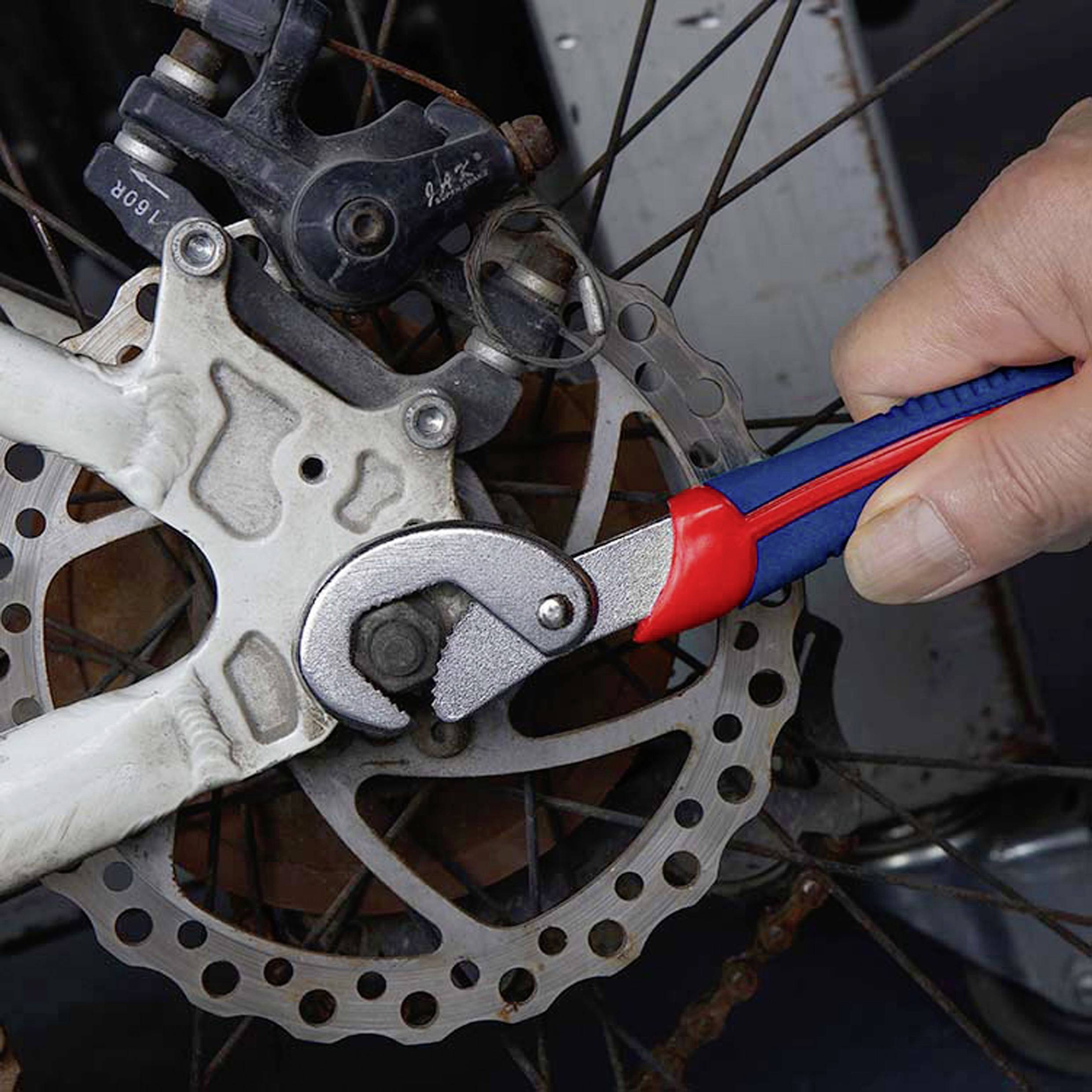 En hand som använder en skiftnyckel för att justera en cykelskivbroms, vilket demonstrerar underhålls- eller reparationsaktivitet på bromsmekanism.