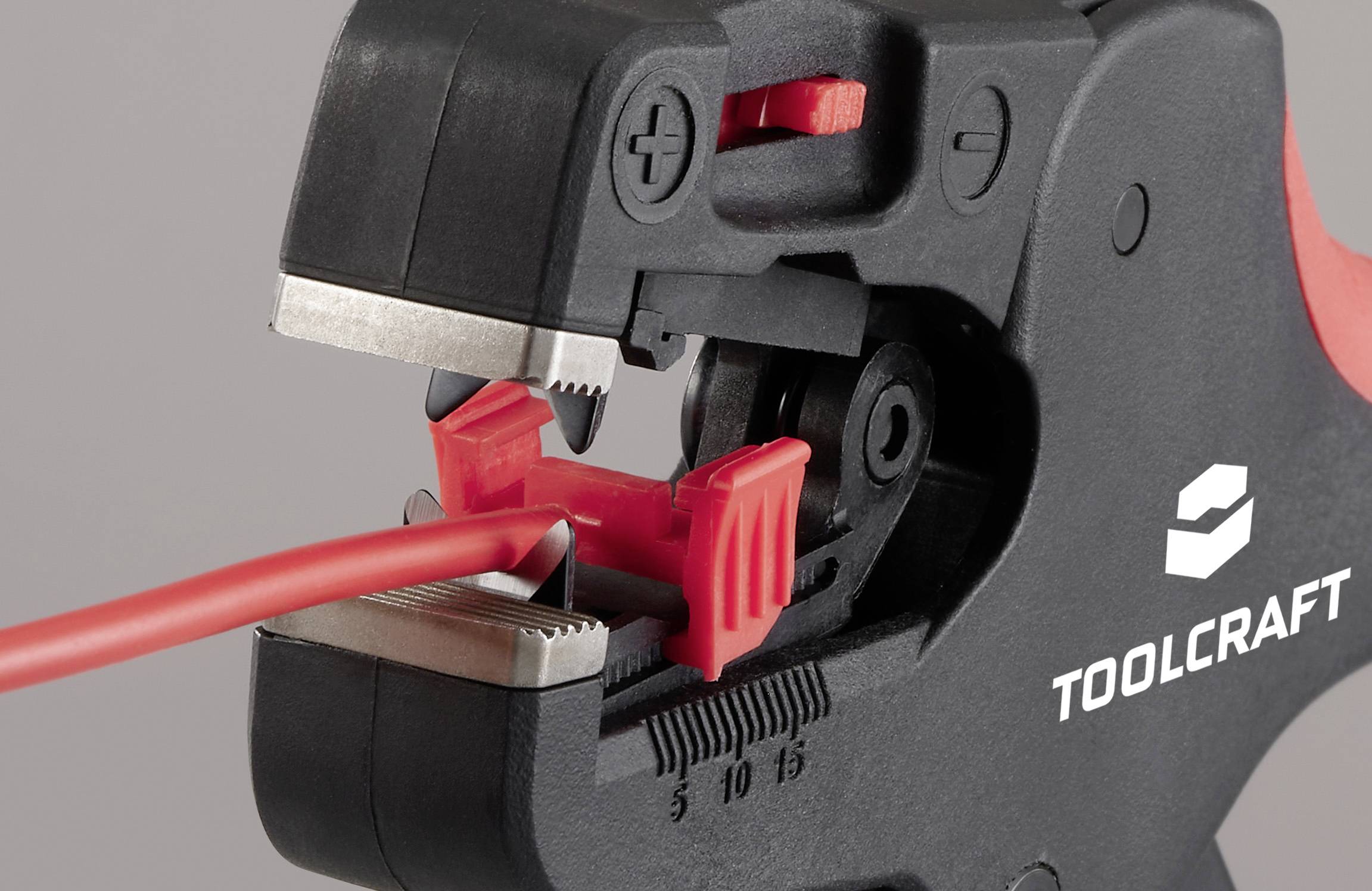 En närbild av ett TOOLCRAFT trådkrympningsverktyg som med precision griper en röd tråd. Verktyget har en klipp- och krympningsmekanism.