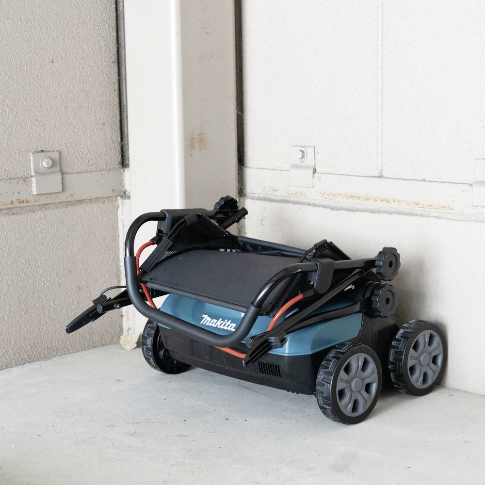 En ihopvikt elektrisk gräsklippare står i ett garage. Det är en modell med fyra hjul som är förvarad yteffektivt.