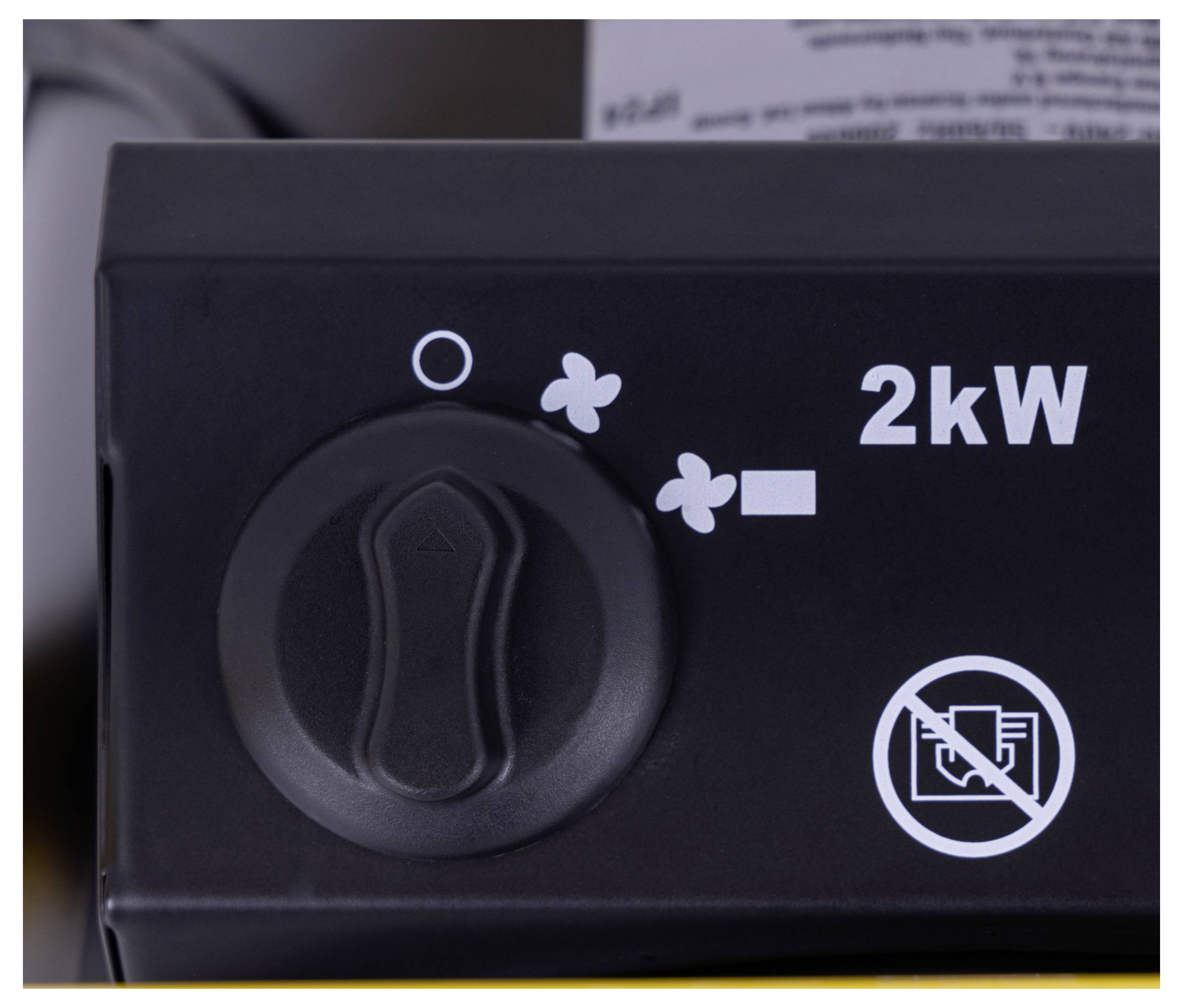 'Närbild av en svart kontrollpanel med en vridreglage och markeringar, som visar en effektinställning på 2 kW och en fläktsymbol. Ingen rökförbudssymbol synlig.'