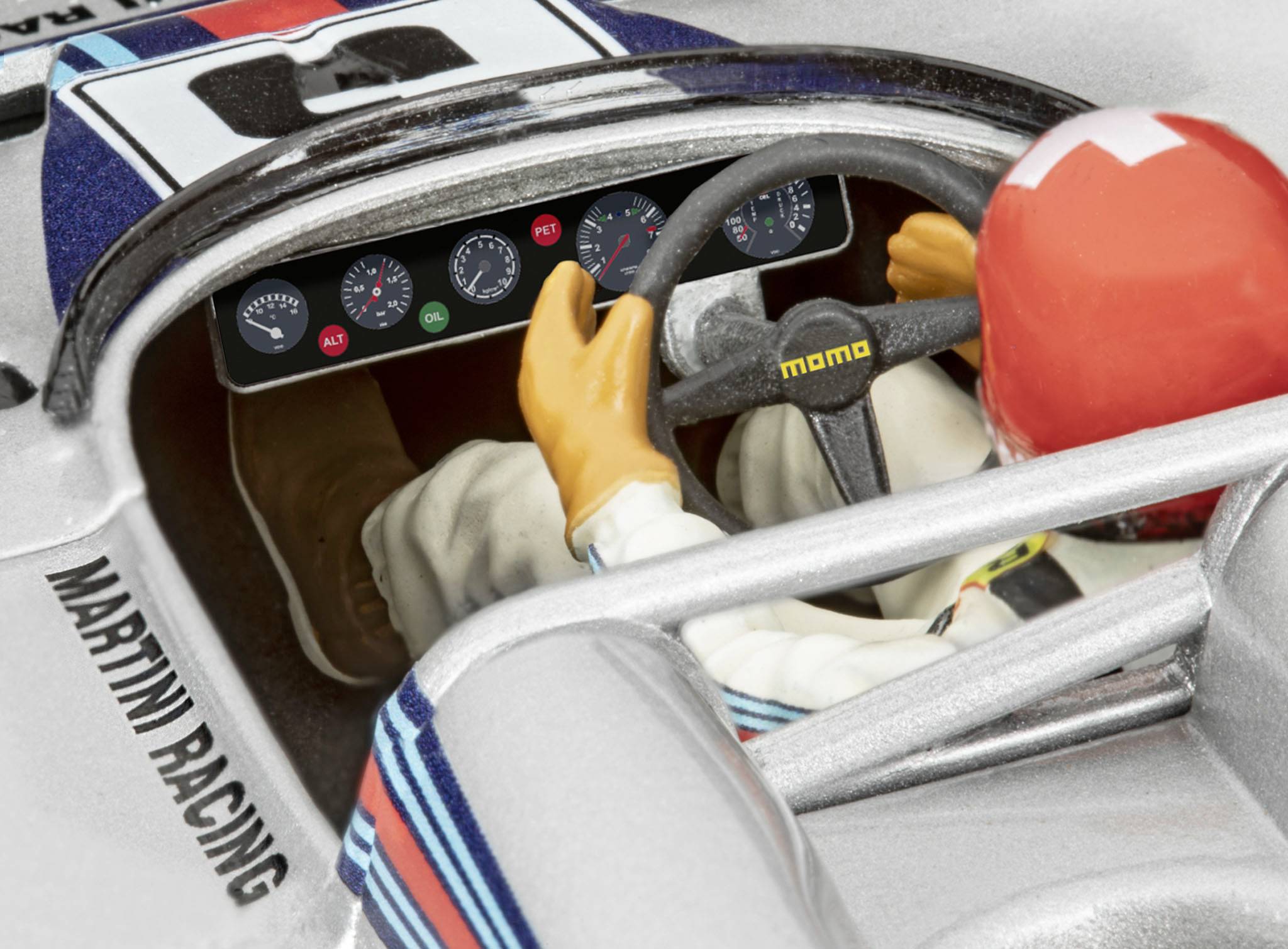 Racerförare i bil med röd hjälm och Martini Racing-märkning, styr på en racerbana. Förarplatsen och instrumentbrädan är synliga.
