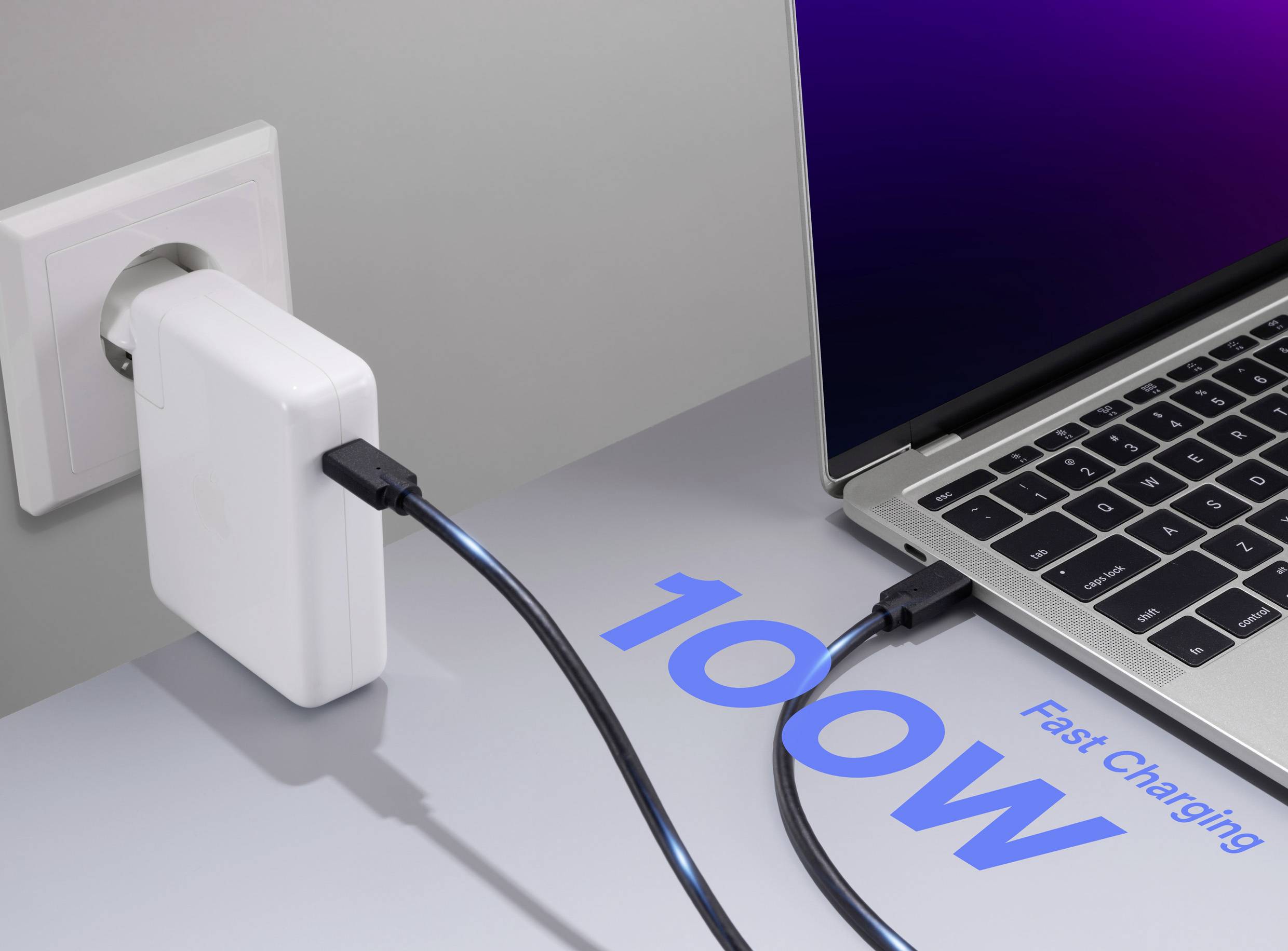 En bärbar dator är ansluten till en nätadapter som är inkopplad i ett vägguttag. Texten på bordet läser '100W Snabbladdning.'