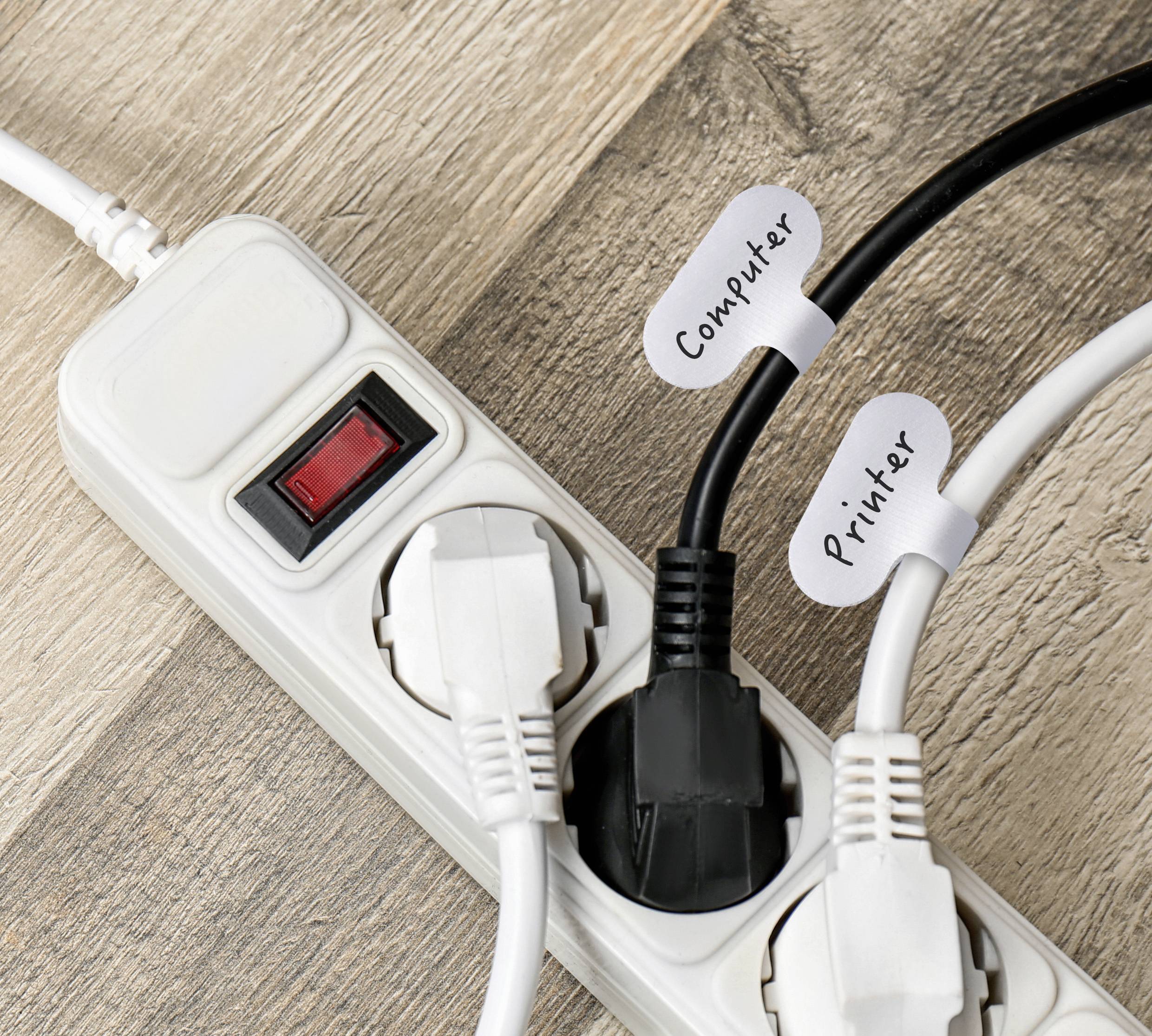 En grenlist med tre anslutna kablar, märkta 'Dator' och 'Skrivare', på en träyta, med betoning på organisering.