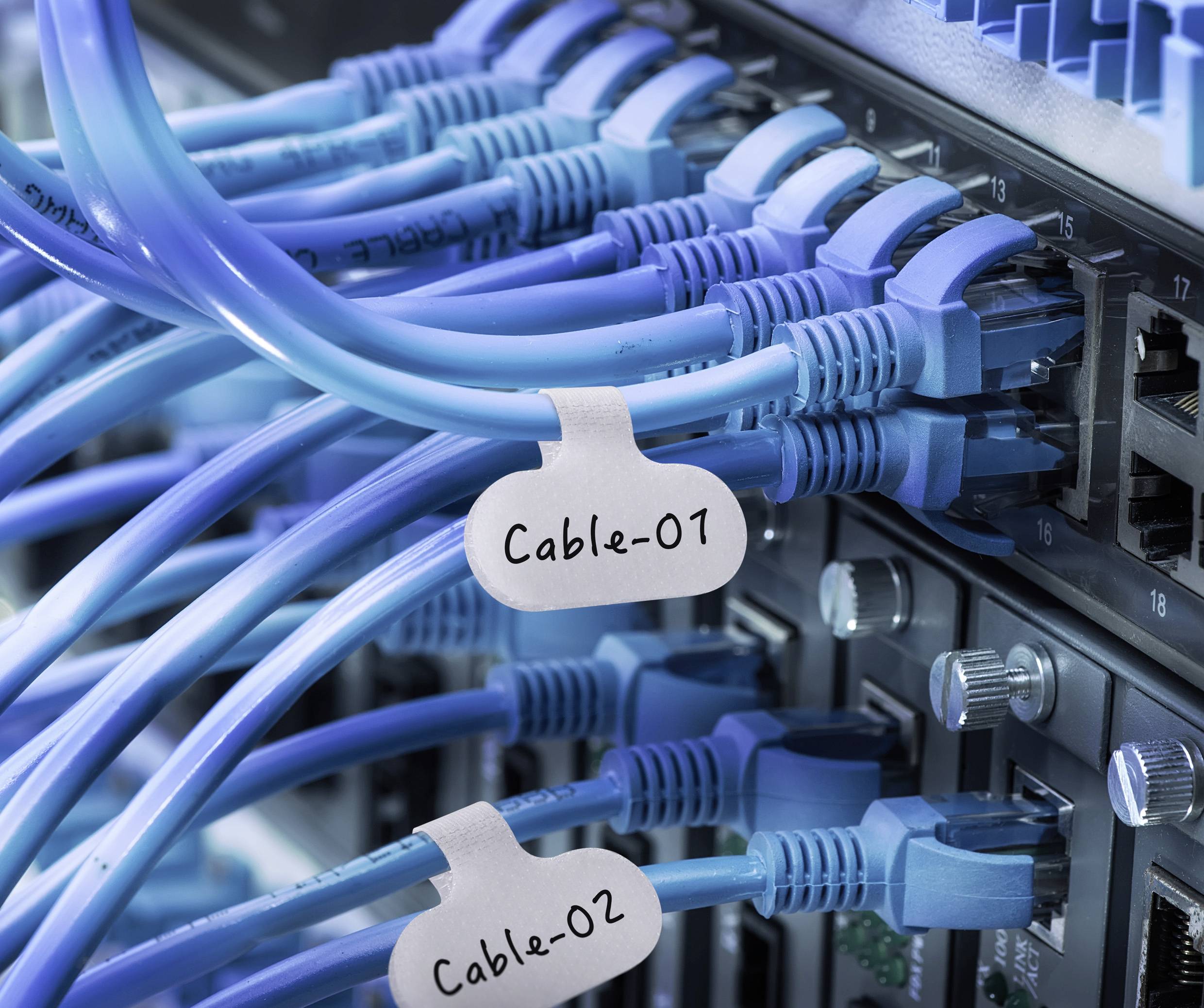 Blå Ethernet-kablar anslutna till en nätverksswitch, märkta 'Kabel-01' och 'Kabel-02', vilket indikerar organiserade nätverksanslutningar.