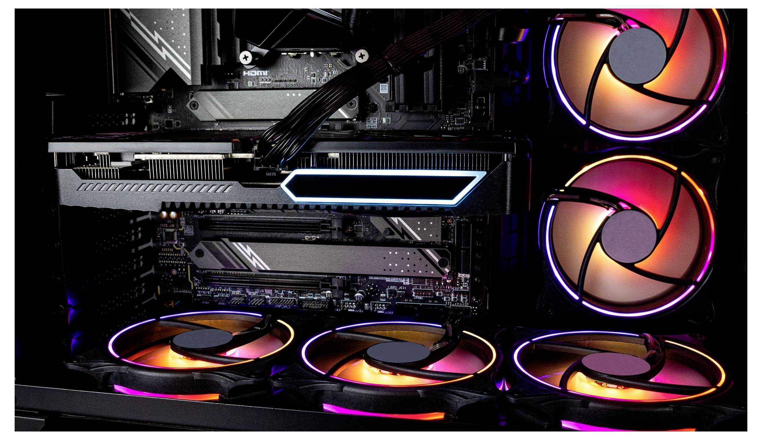 En spelddator interiör med RGB-belysning, som visar ett grafikkort, kylningsfläktar och moderkortkomponenter, illuminerade i olika färger.