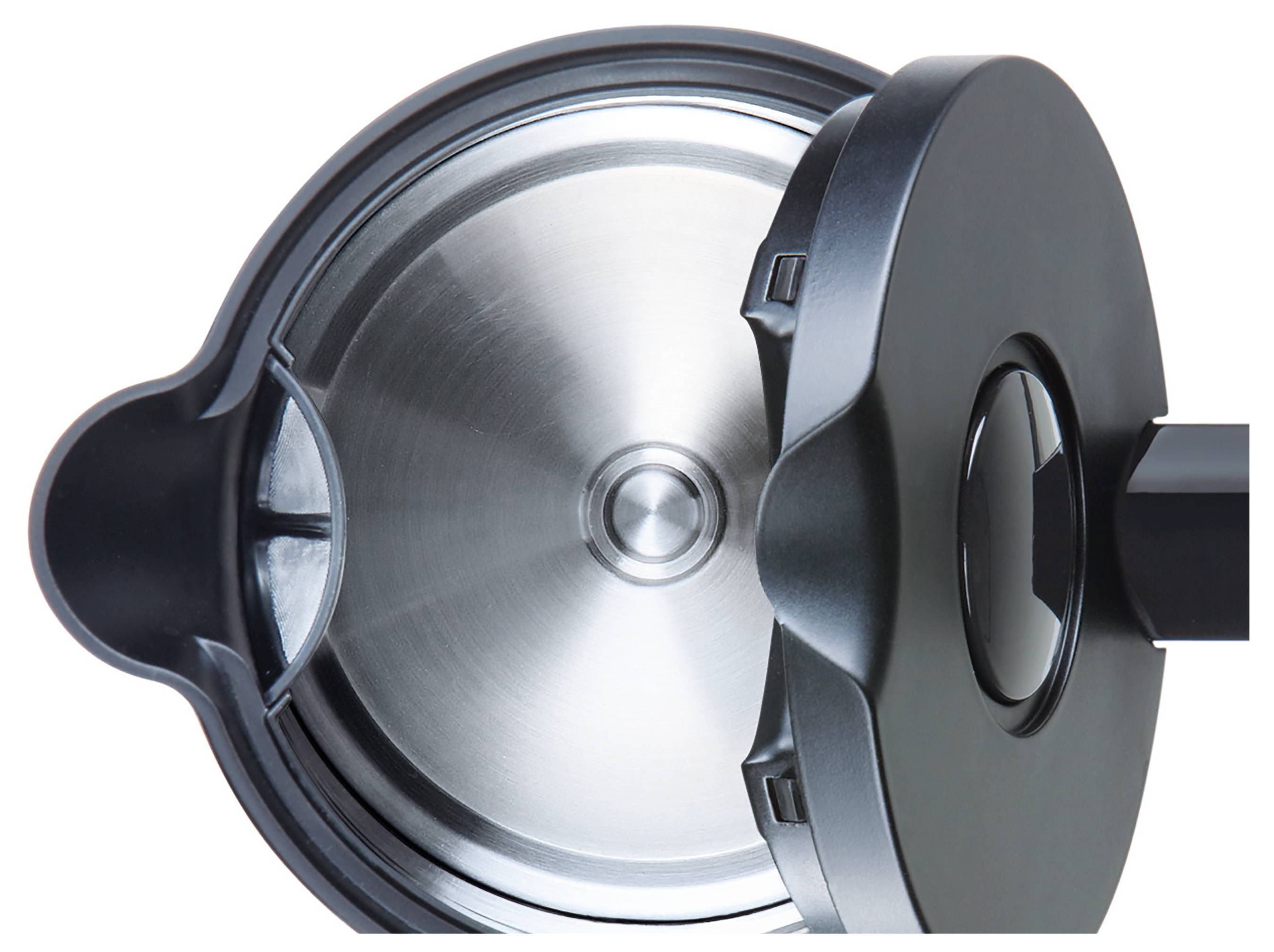 En närbild av ett tryckkokarlocks insida, där den cirkulära metalliska interiören och det mörka handtaget visas mot en vit bakgrund.